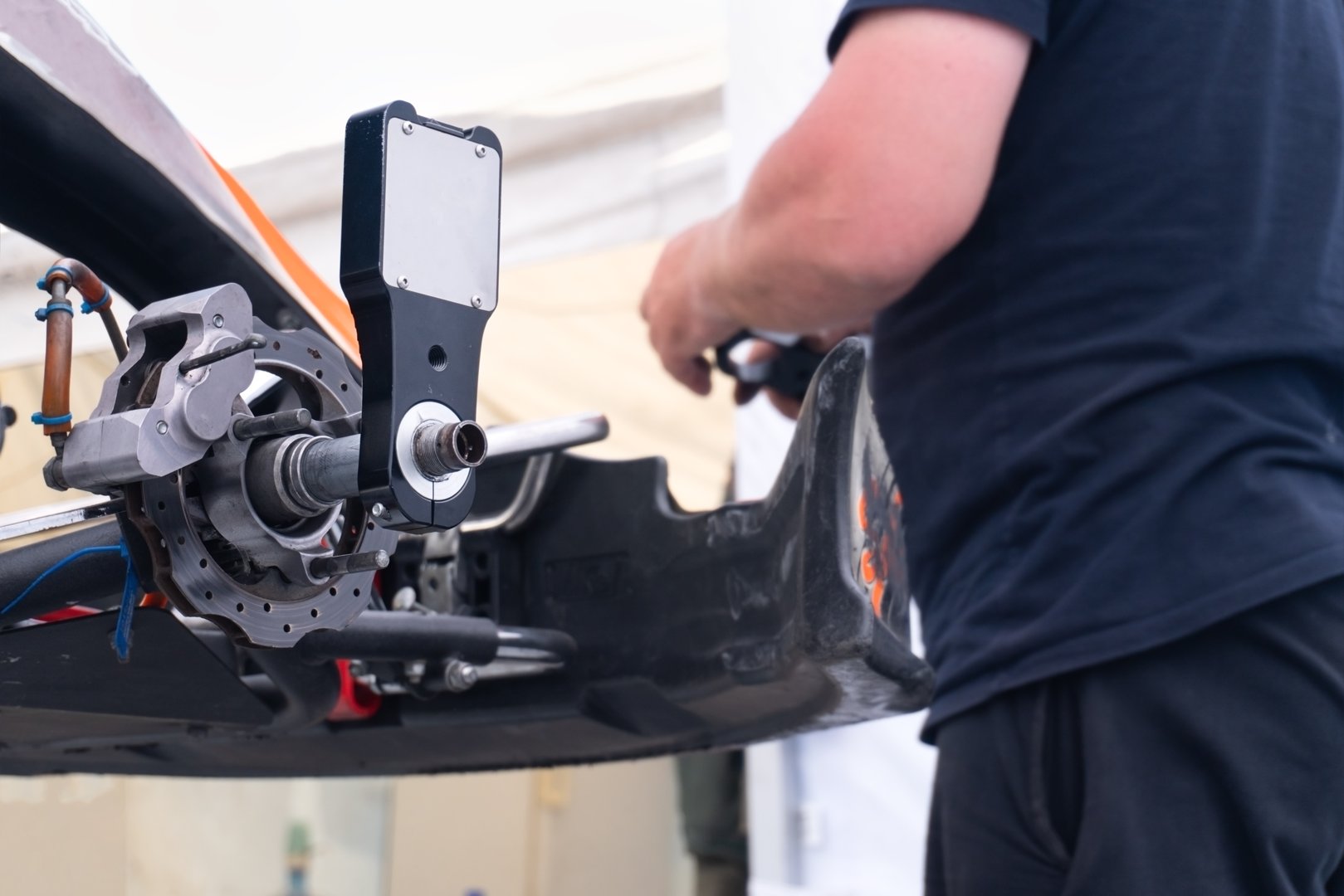 A mechanic installs a laser shaft alignment device. Preparing a racing car for competitions