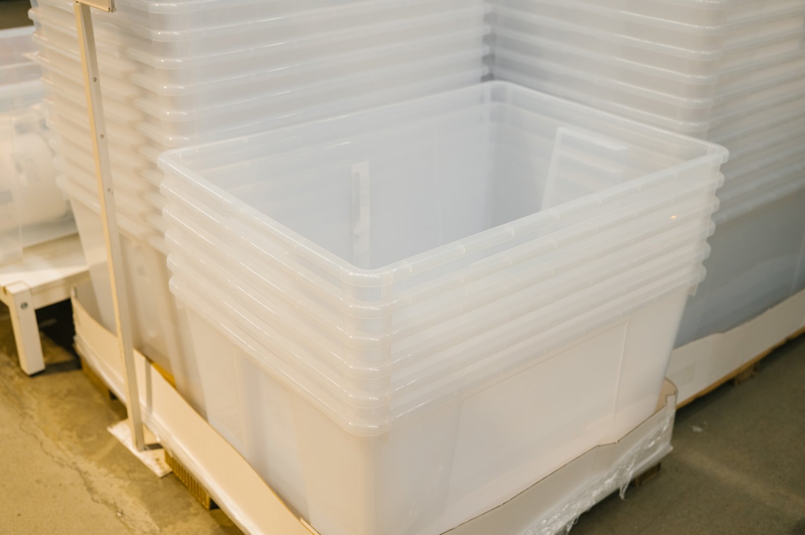 Stacked clear plastic storage bins on warehouse pallet.