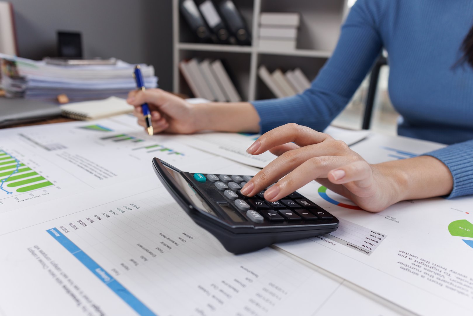 Young Asian businesswoman uses a calculator to calculate business principles. Accounting statistical concepts at the office starting a financial business, calculating accounting online marketing.