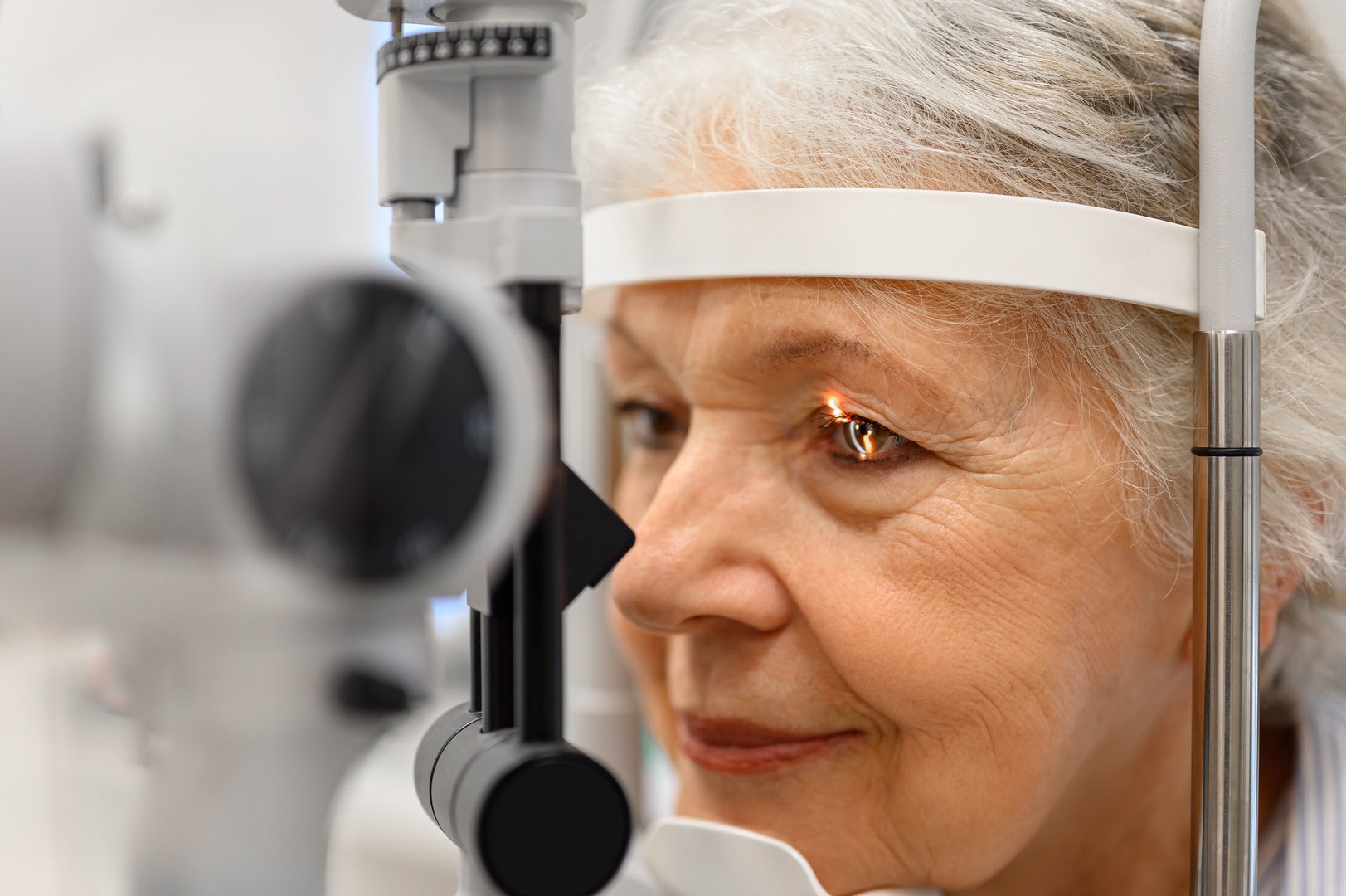 Close-up of mature patient undergoing detailed eye examination with slit lamp and light at ophthalmology clinic