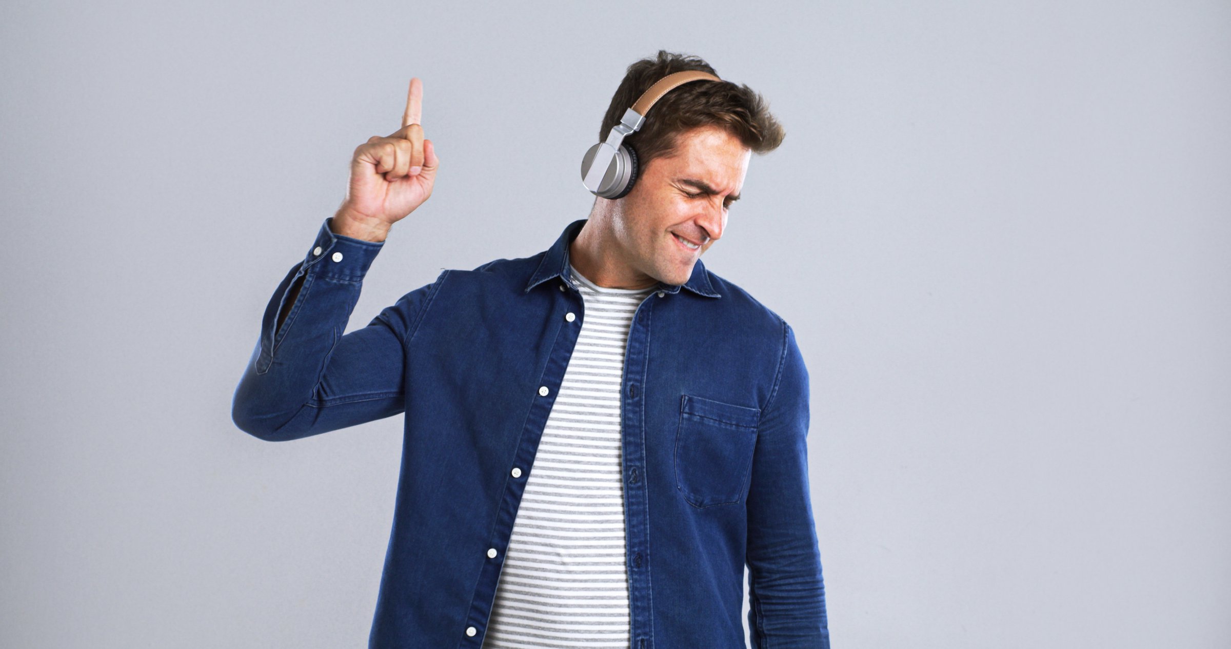 Music, headphones and man with dancing for fun, online streaming or radio with mockup space in studio. Energy, listening with audio tech and sound for rhythm with male person on white background