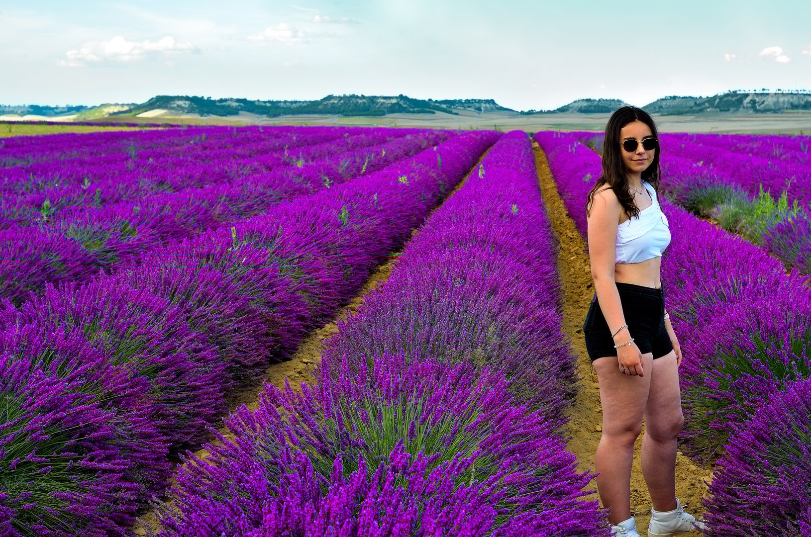 Joven mujer en campo de lavanda colorido en verano oliendo la flor,
Valladolid, Castilla y León, España