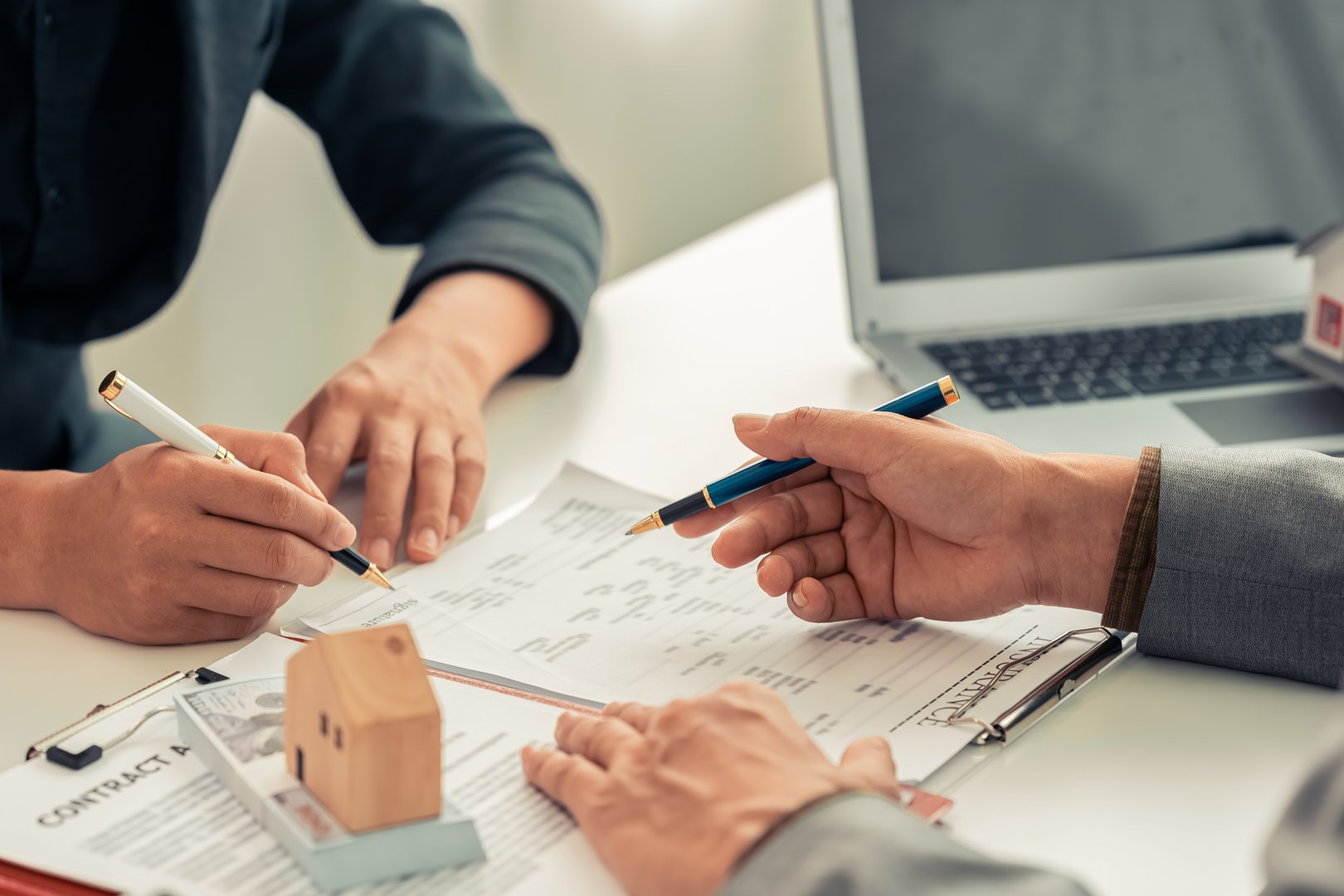 Real estate businessman presenting home loan and presenting house to customer after discussing and signing contract with approved application. Close up.