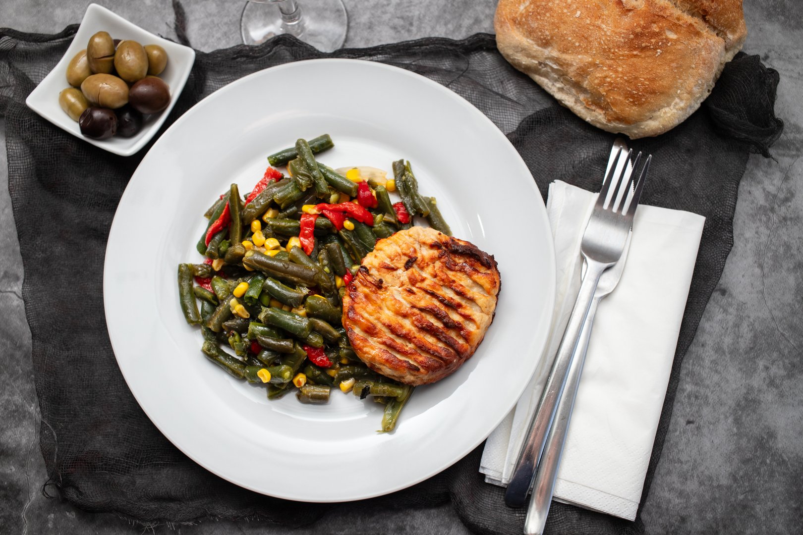gried chicken burger with boiled green beans on white plate