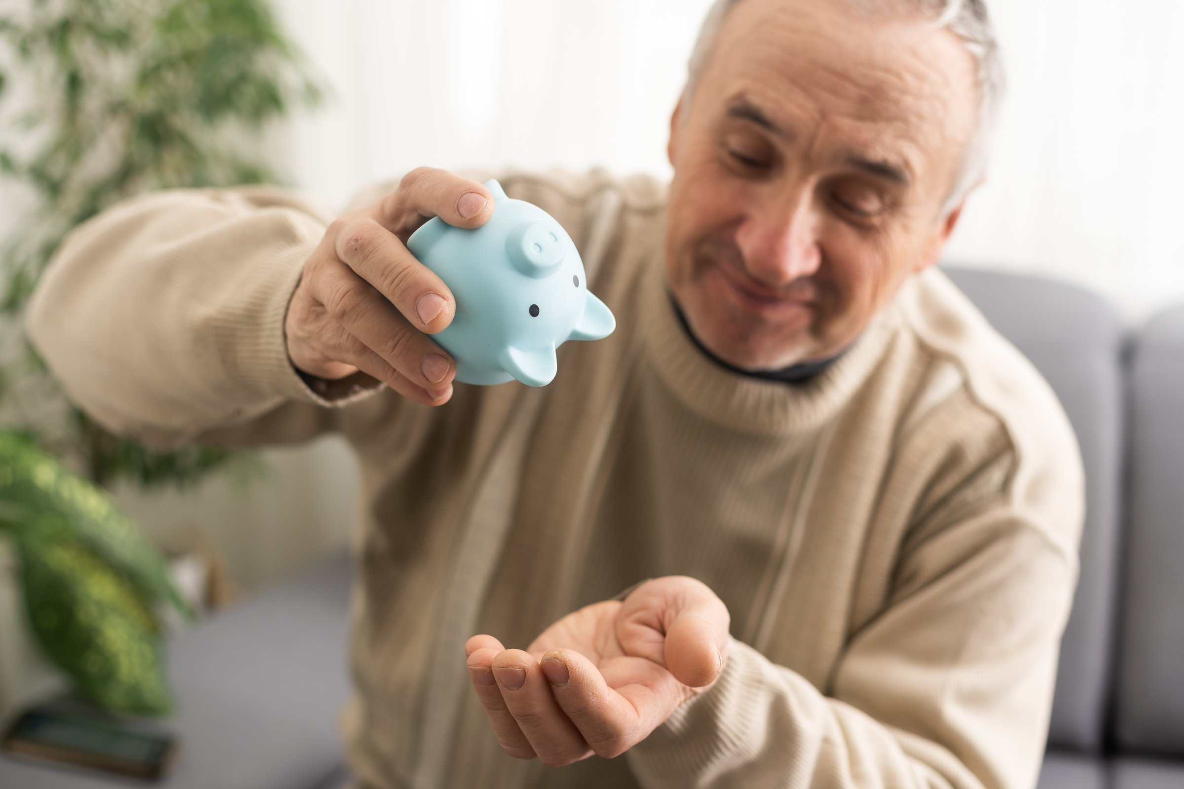 an elderly man is holding a piggy bank.