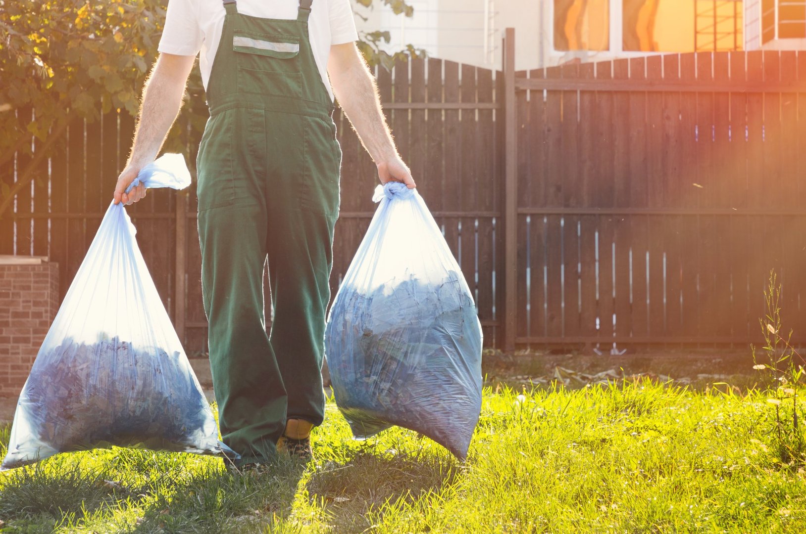close-up of the gardener ,in the hands of bags of compost .sunlight on the right.