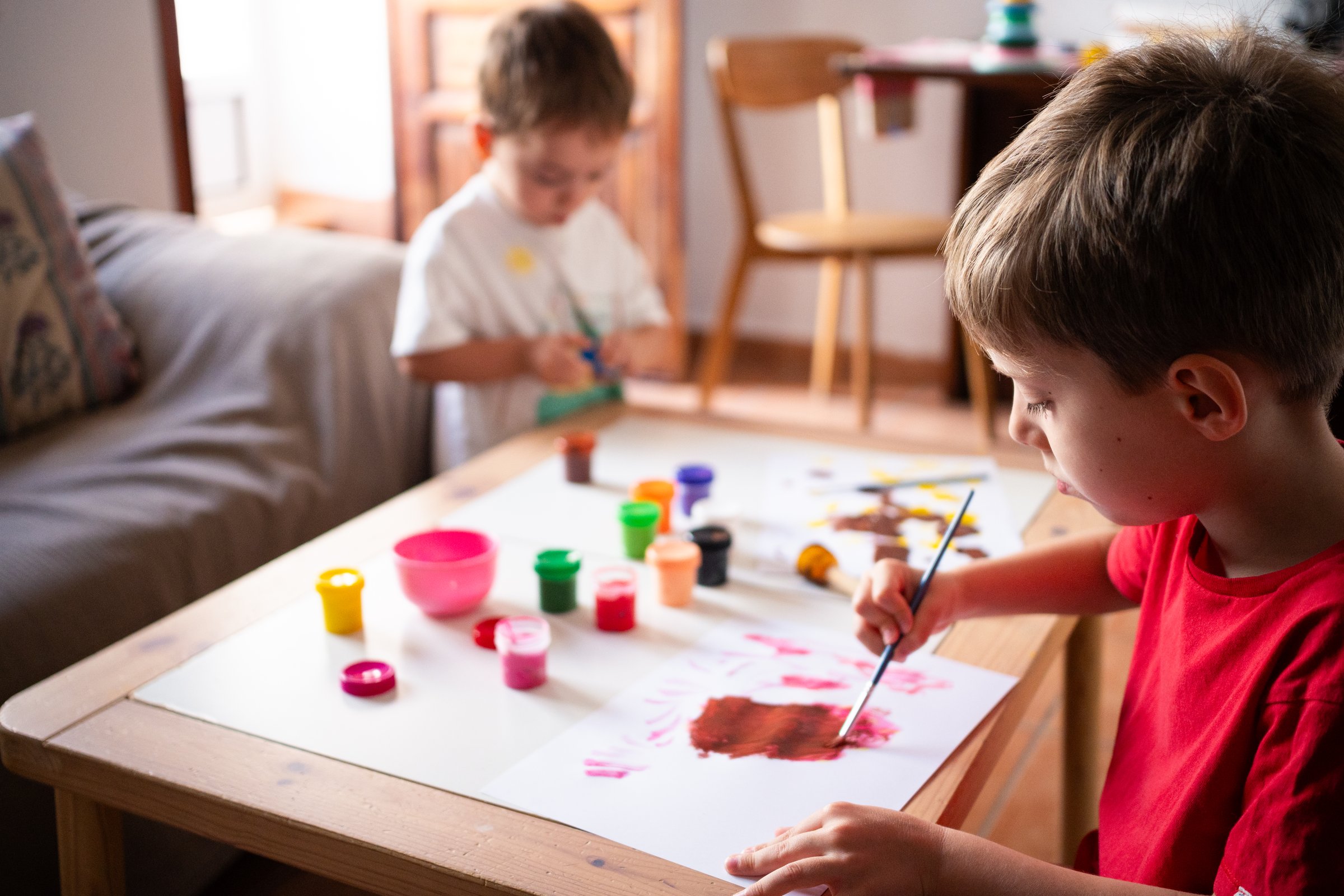 Two children painting together in a warm indoor space