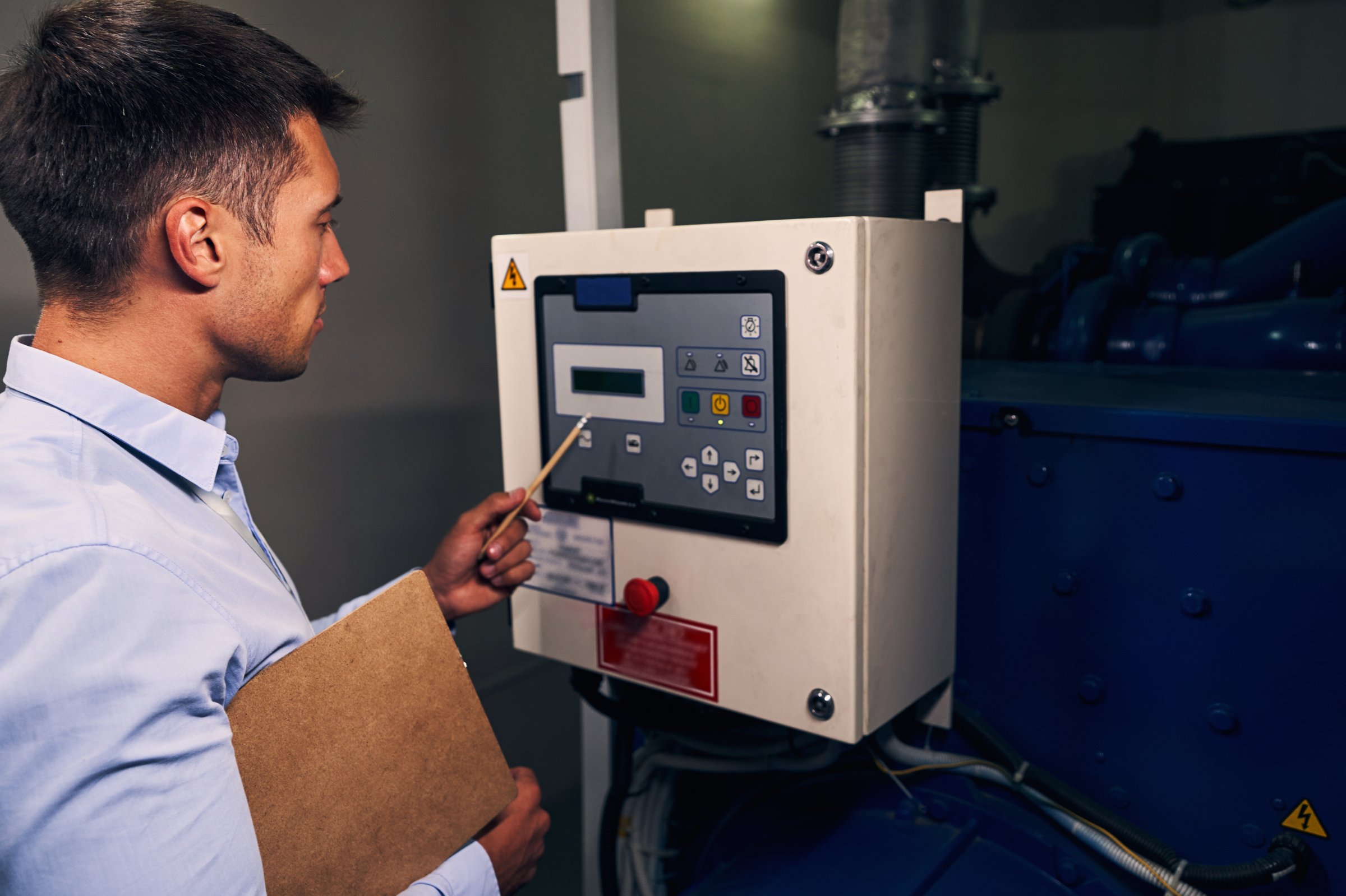 Focused Caucasian maintenance engineer staring at control panel of diesel generator