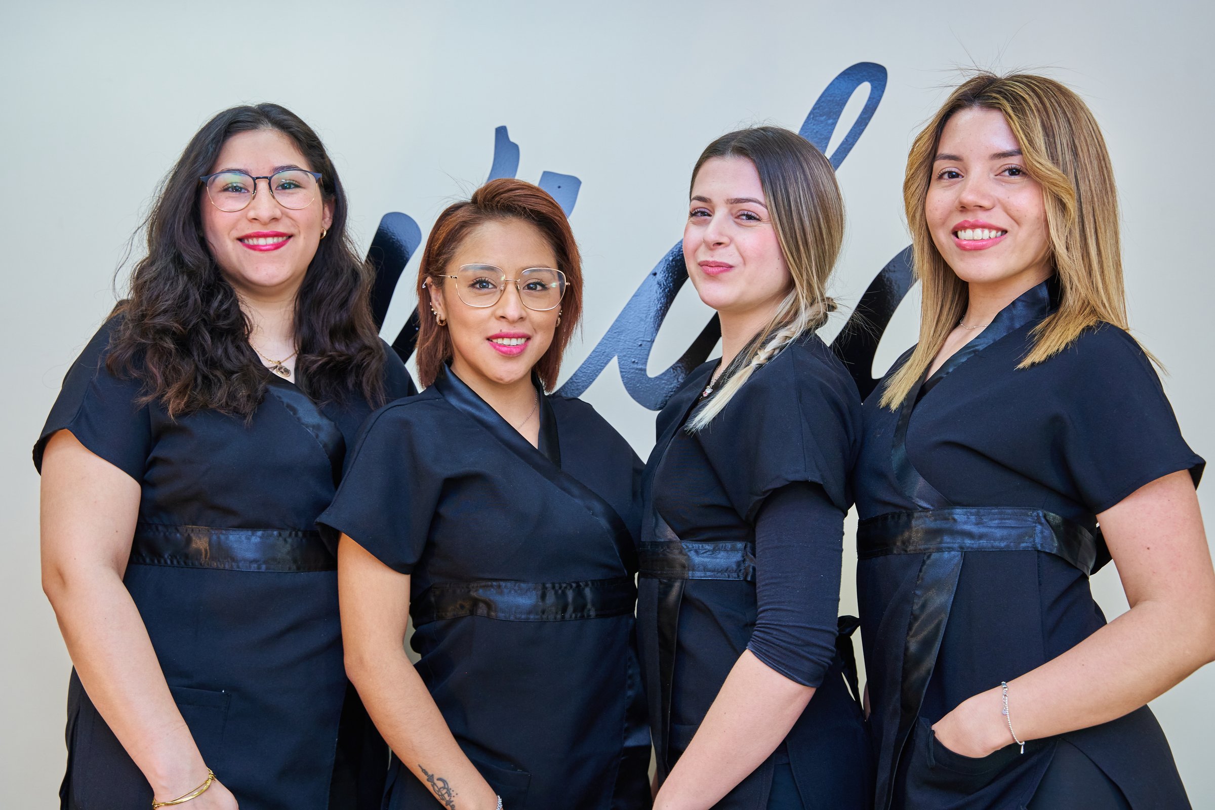 Four women in black uniforms are posing for a picture. They are all smiling and seem to be happy