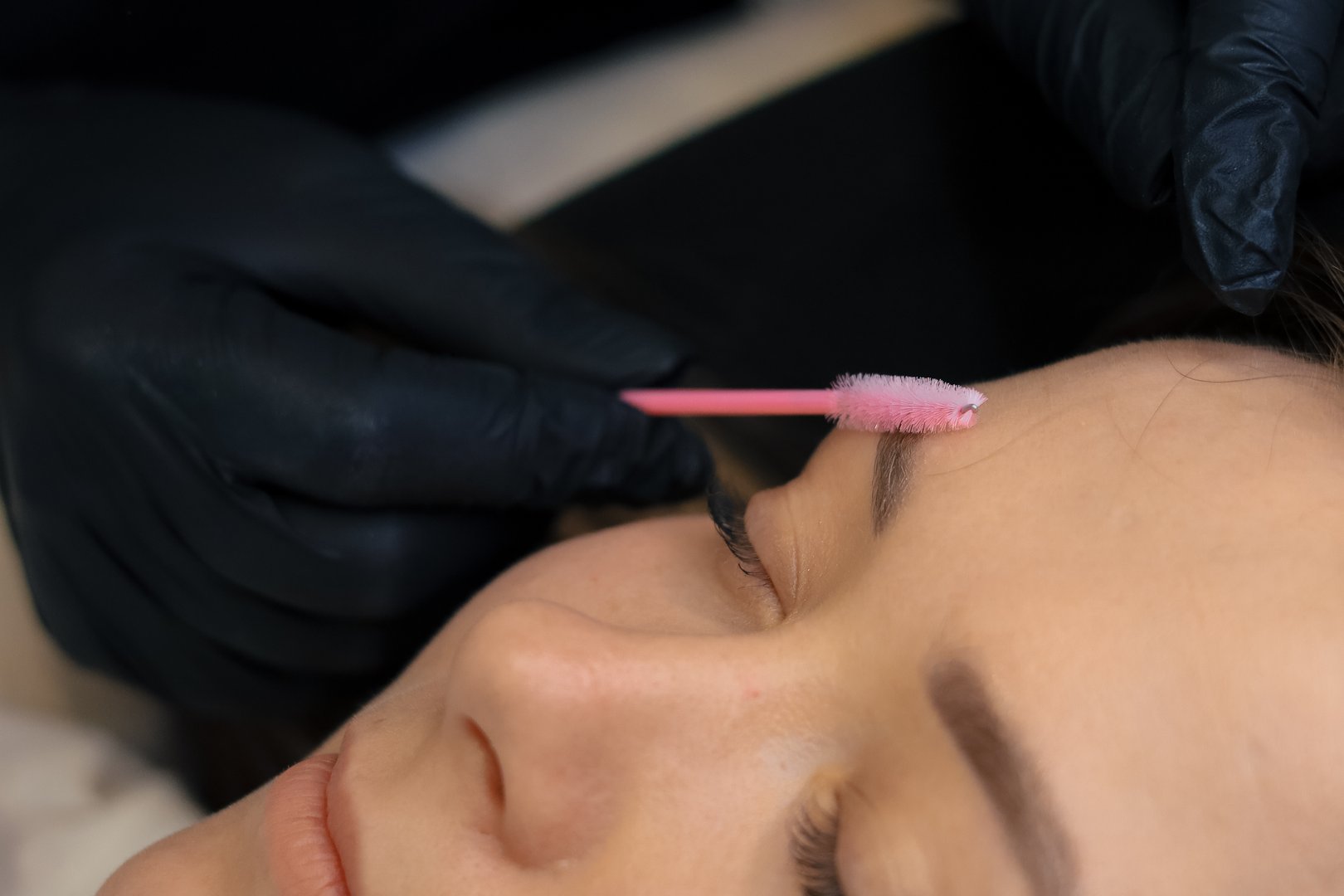 Master in gloves applying white pencil before permanent makeup procedure .