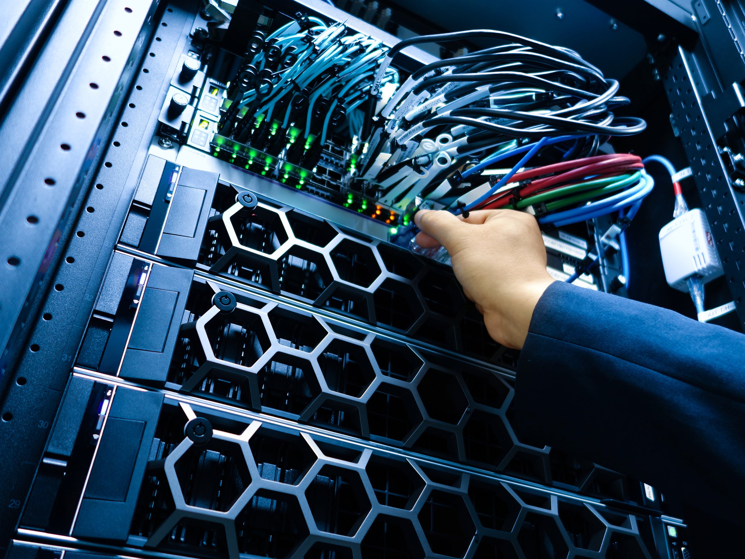 A technician performs maintenance on a server rack, managing cables and hardware for optimal performance and connectivity in a modern data center environment.