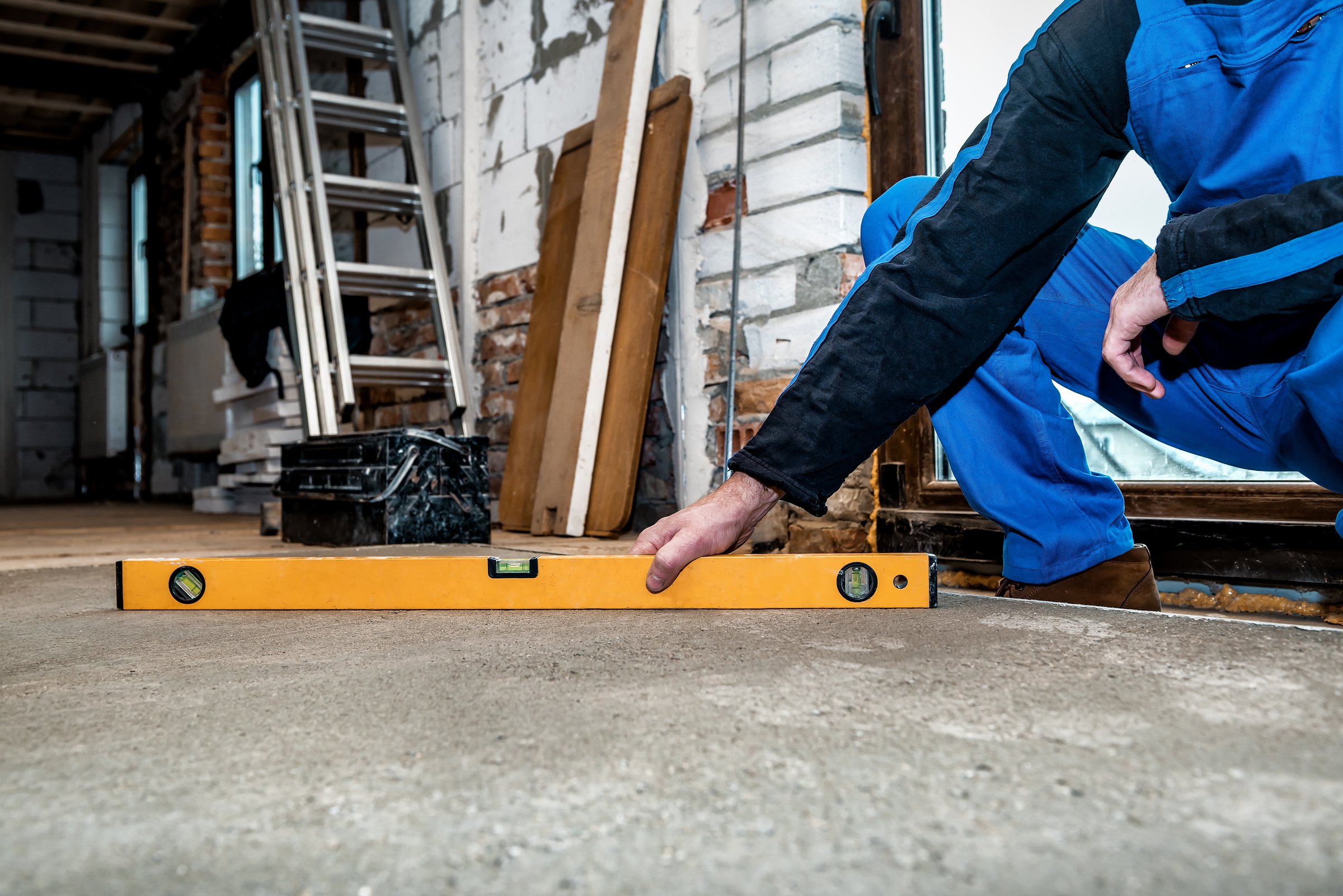Worker measuring level of floor for foundation repair