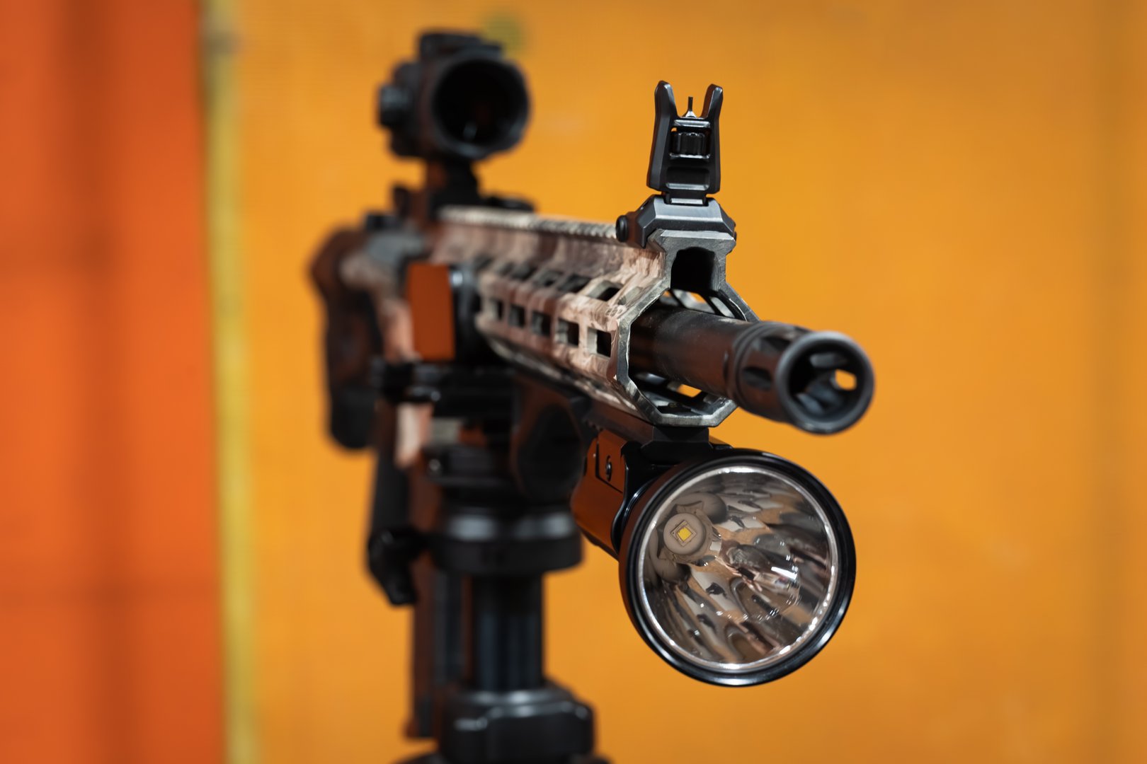 Close-up of a large, powerful tactical flashlight mounted on the rail of a modern custom rifle.Close up photo