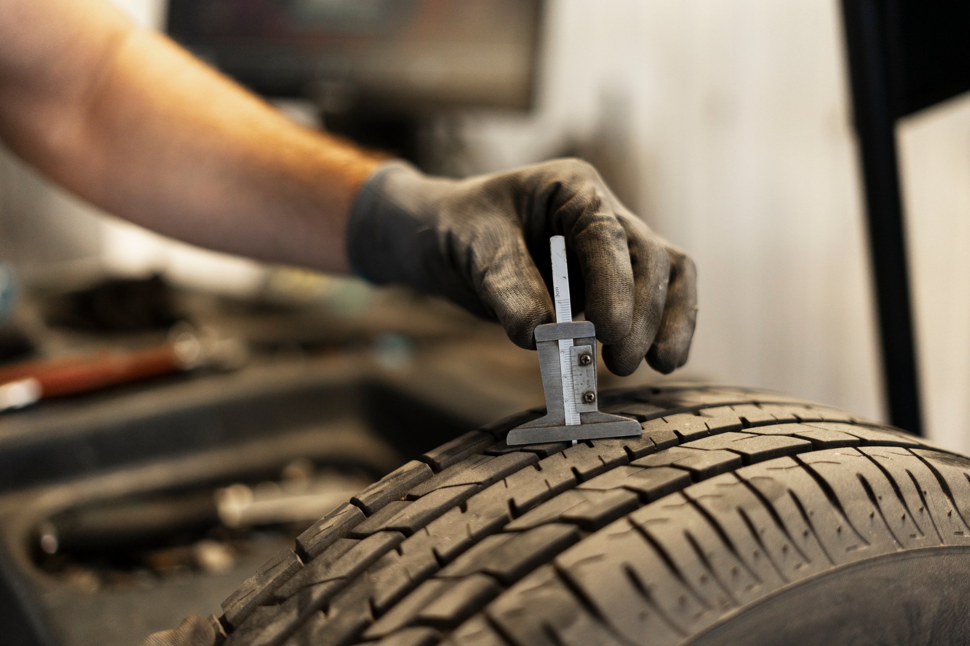 Mechanic is using a caliper to check the tread depth of a tire to determine if it needs replacing