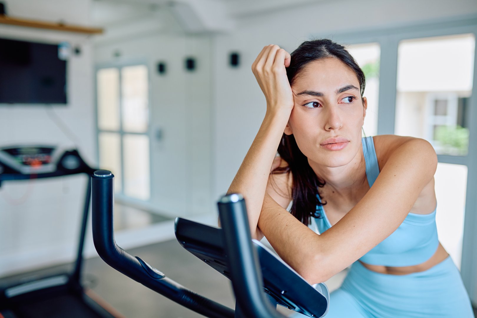 Young woman resting on an exercise bike at a modern gym