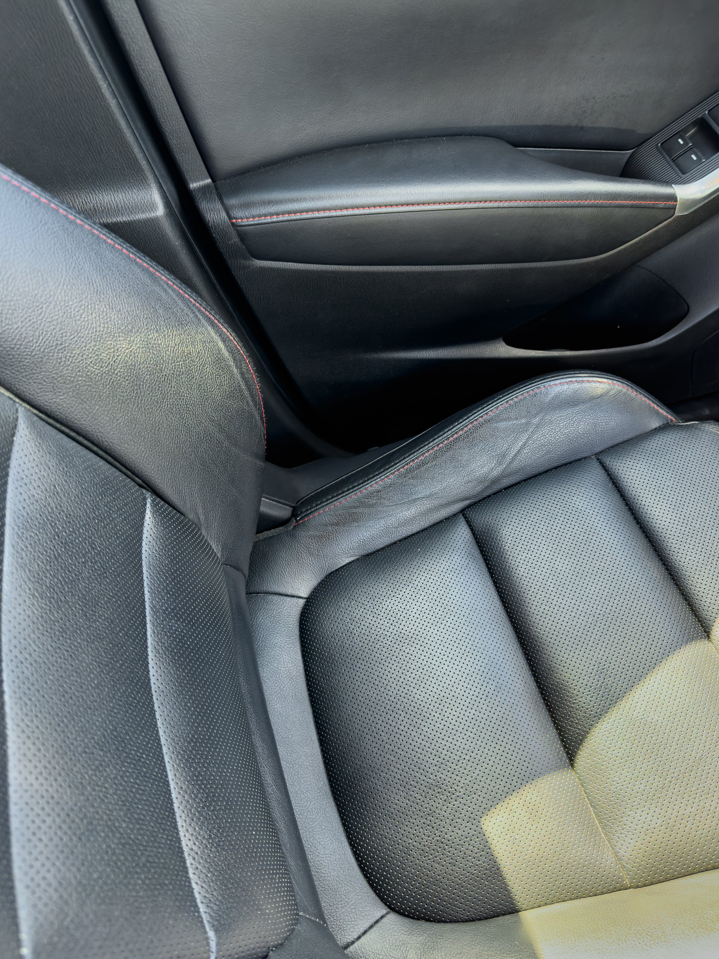 A close-up view of a luxurious black car seat, highlighting its textured material and ergonomic shape. The interior reflects a modern design suitable for stylish travel.