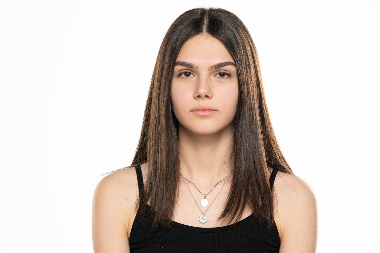 portrait of a beautiful teenage girl with long straight hair and no makeup on a white background