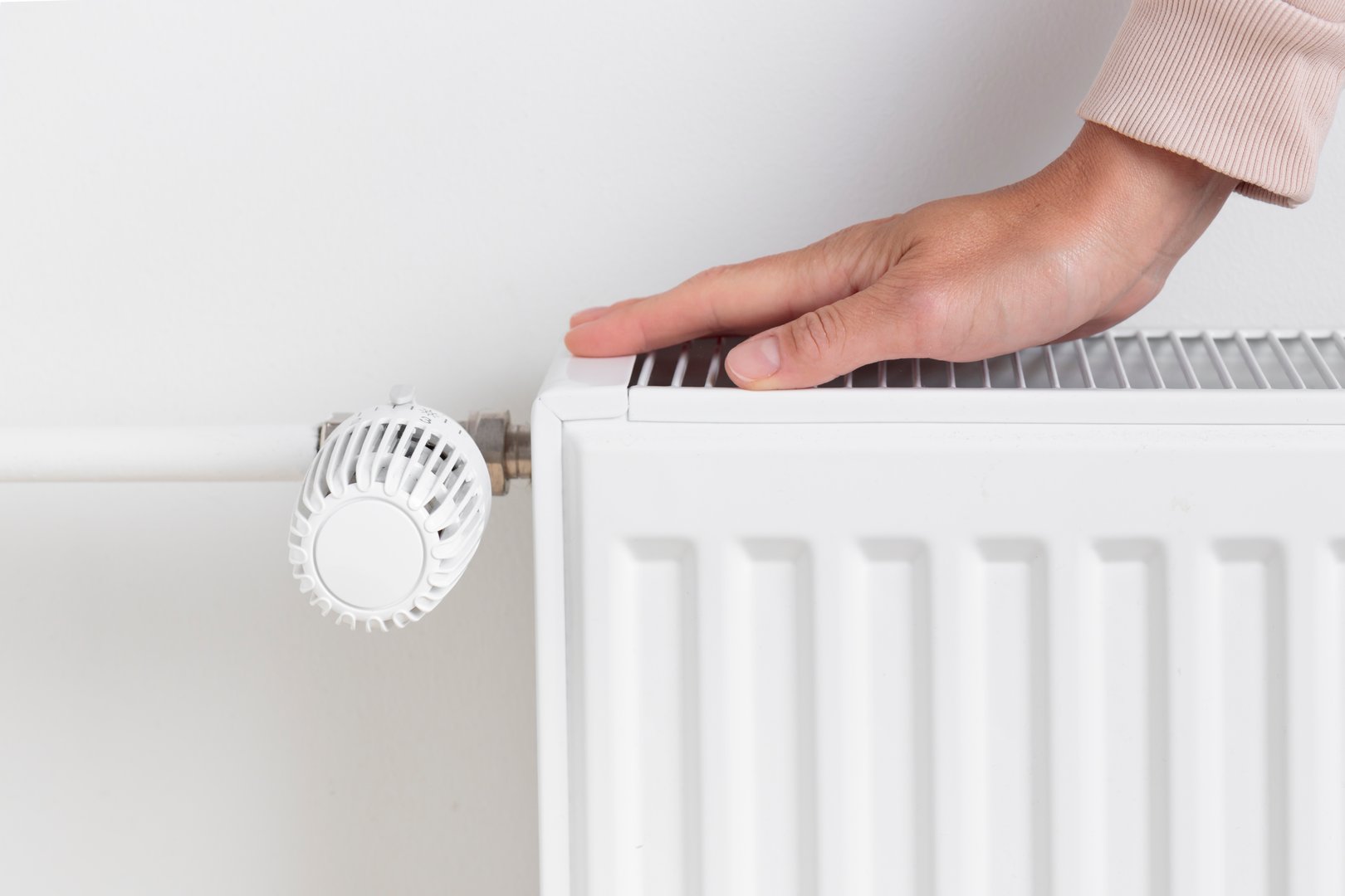 A woman warming her hands on a heating radiator, the concept of conserving heat and energy and the importance of resource management during colder seasons. seeking warmth, energy efficiency, and mindful living