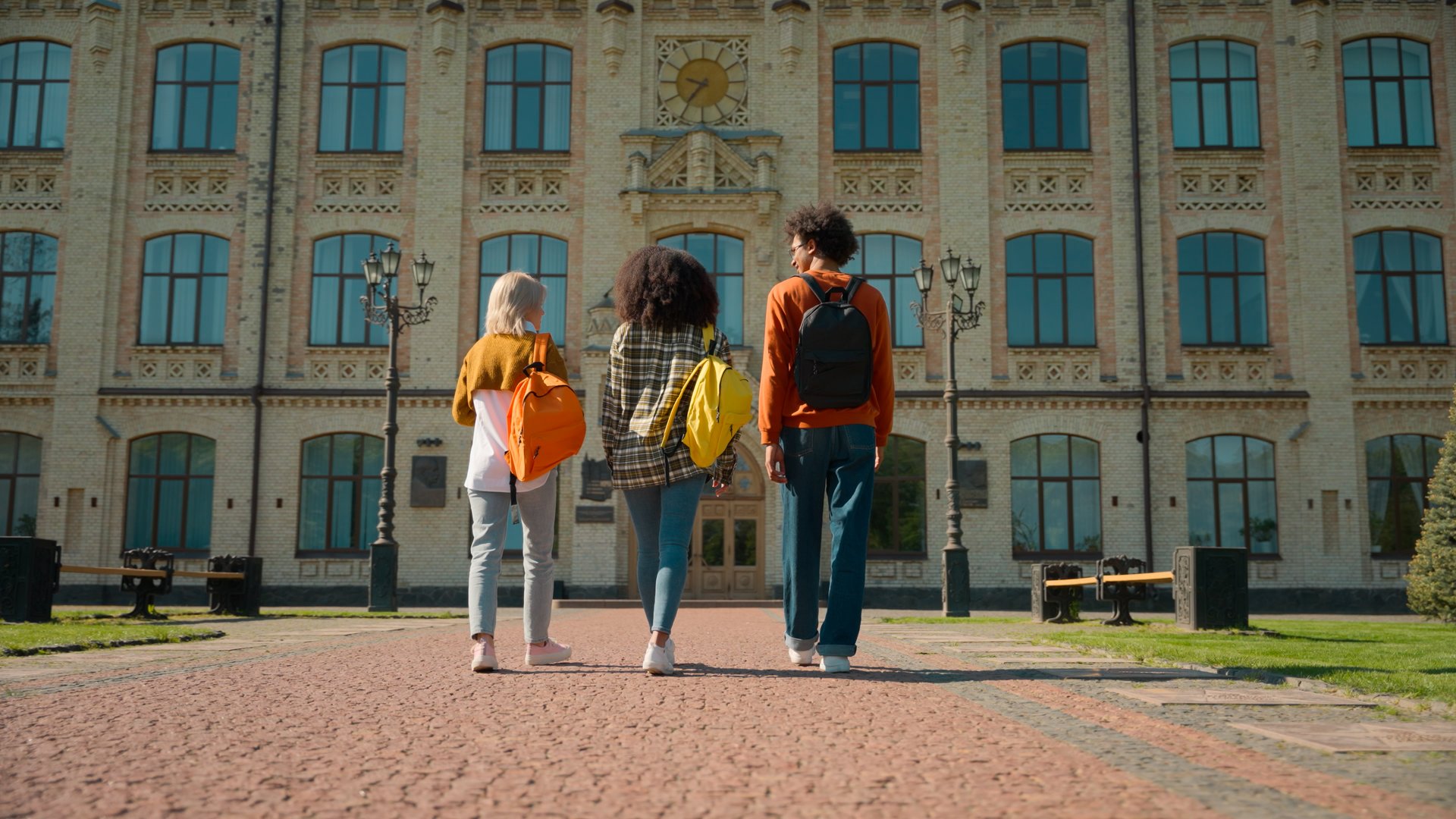 Back view three multiracial people outside go to class lesson studying together students diversity friends man guy male Caucasian African females women girls walking outdoor school university college. High quality 4k footage