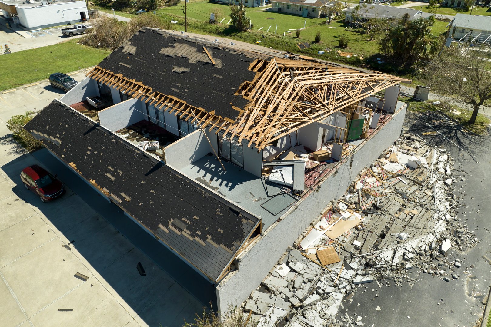 Wind destroyed house roof and walls with missing asphalt shingles after hurricane Ian in Florida. Demolition of building after natural disaster.