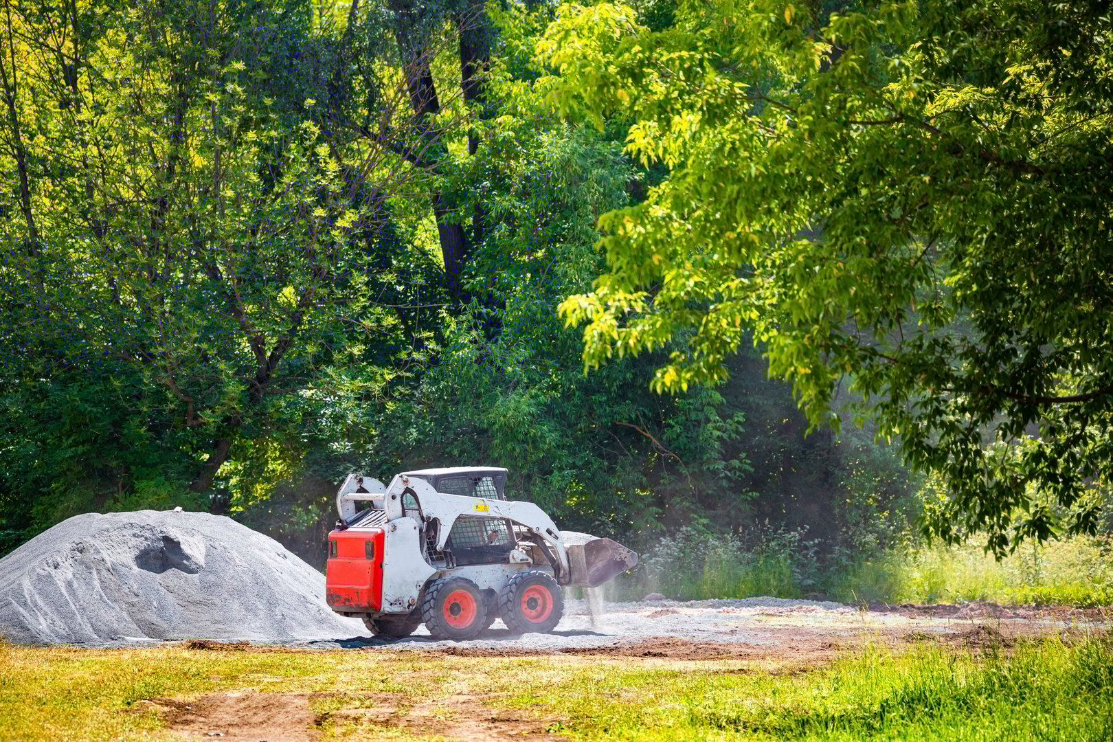 Moscow, Russia - June 22, 2023: tractor transports crushed stone in a bucket. landscaping park