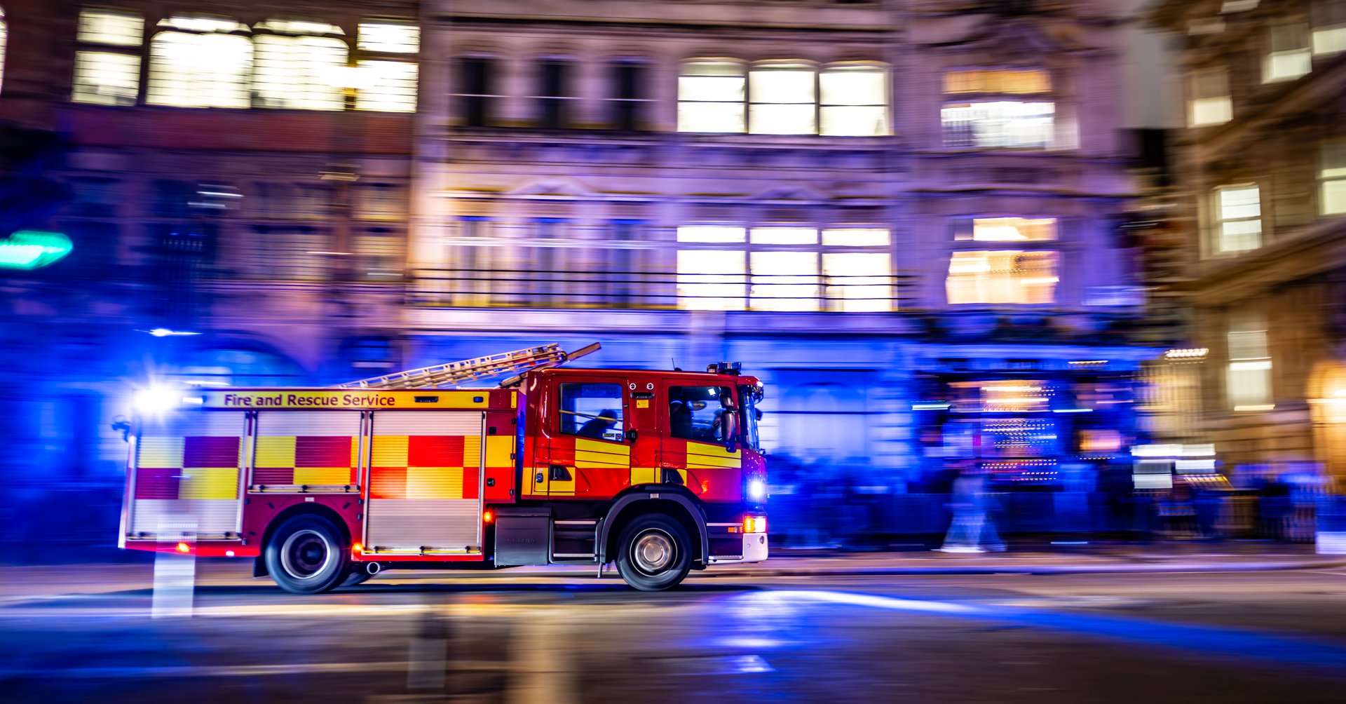 fast firetruck at night with it's emergency lights on the way to a rescue or attend a situation at night in London center with unrecognizable crew in it. with effect of motion and panning and with copy space around it for a text.