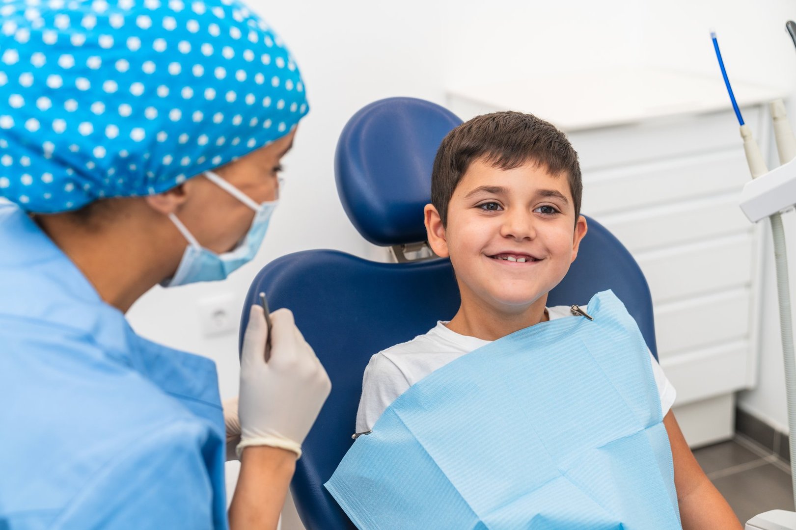 A child smiles while sitting in the dental chair, feeling confident after his checkup with the hygienist. Concept of positive pediatric dental care.