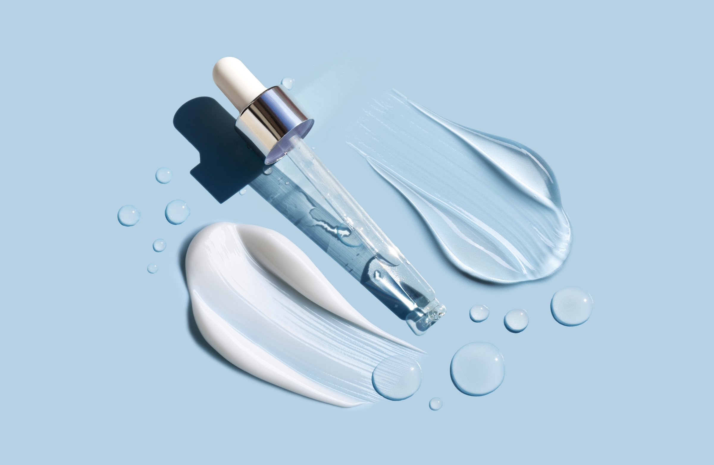 samples of cosmetic care products smear of cream and gel, serum texture, texture cosmetic products on light blue background