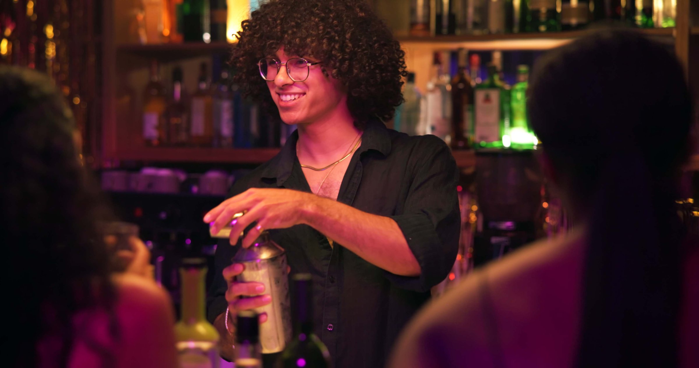 Barman, shaker and people for drinks at nightclub with bottle service, skills and liquor for event. Person, bartender and patron with mixing, alcohol and spirits for cocktail, catering or job at pub