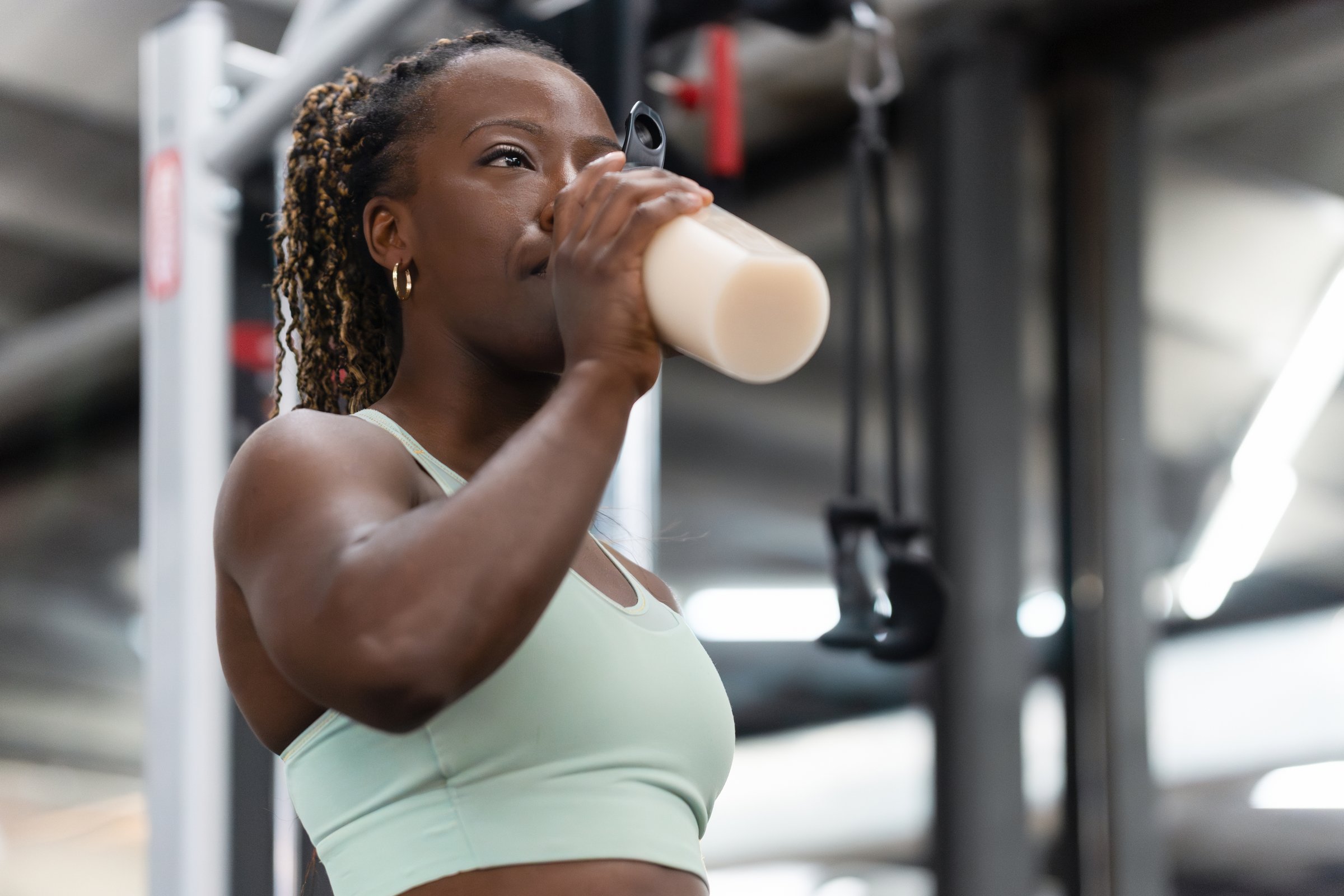 Young african american woman takes a break from her workout to hydrate with a protein shake