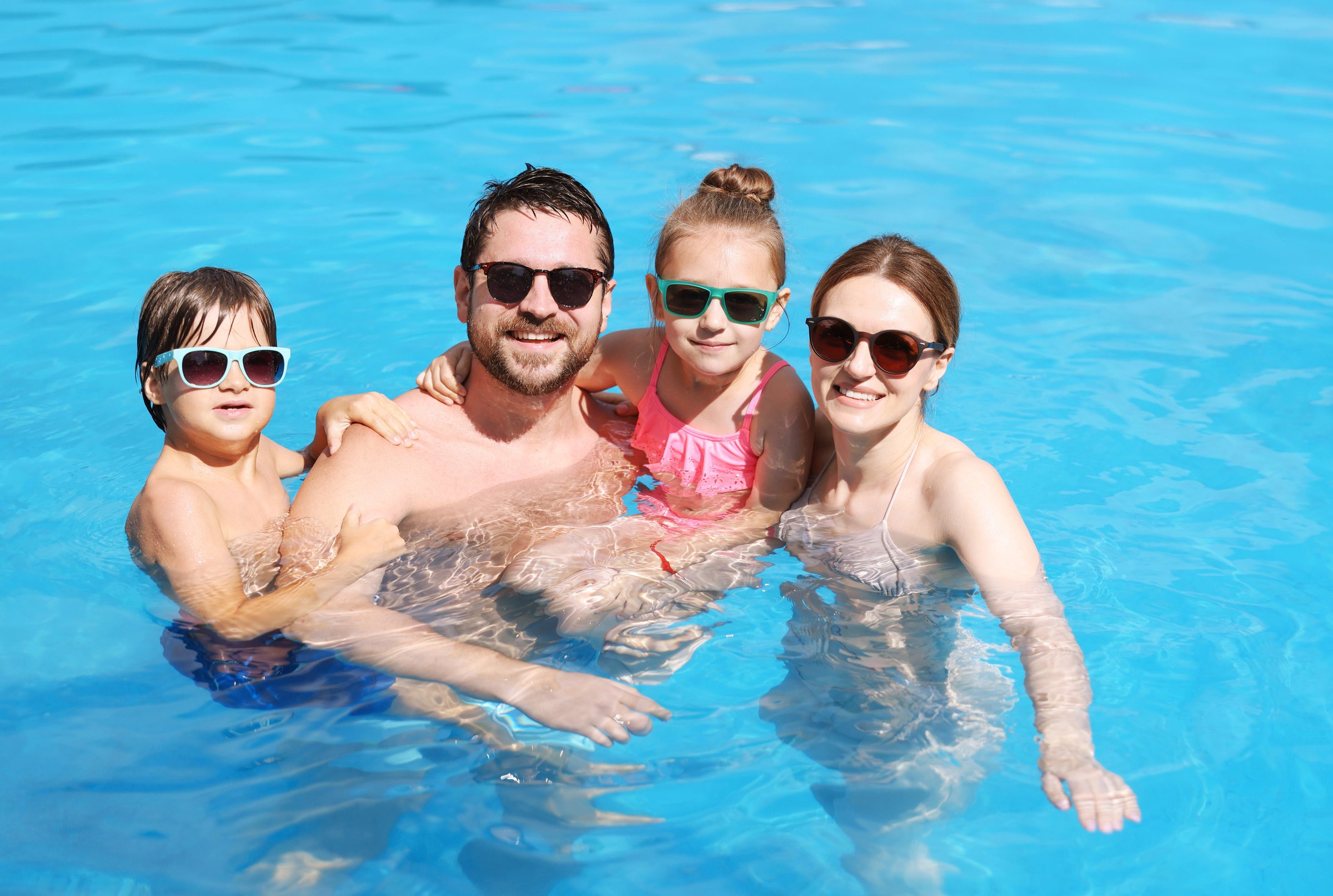 Happy family resting in swimming pool outdoors