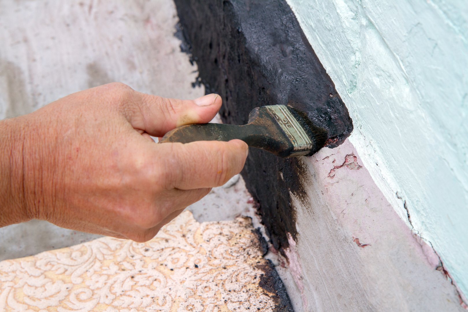 Painting the foundation of the house with mastic for waterproofing