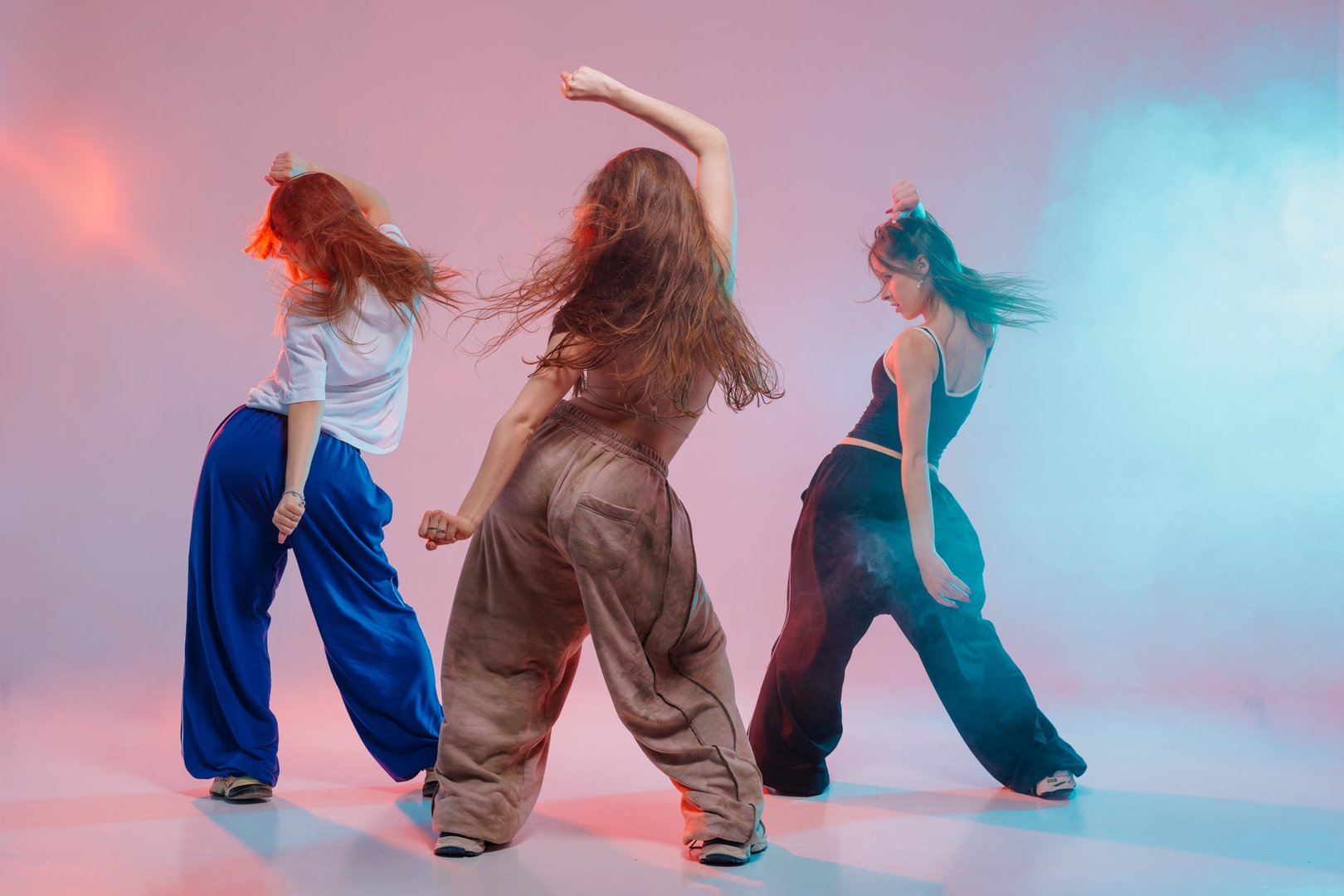 Group of young women performing jazz funk dance with expressive moves in a vibrant studio with colorful lighting and energy