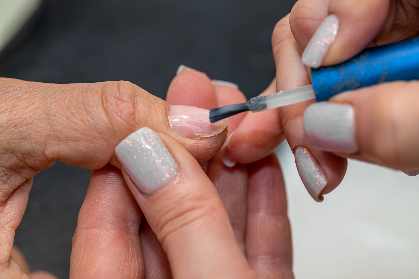 Nail care procedure in a beauty salon. Female hands and tools for manicure, process of performing manicure in beauty salon. Concept spa body care. Gloved hands of a skilled manicurist cutting cuticles