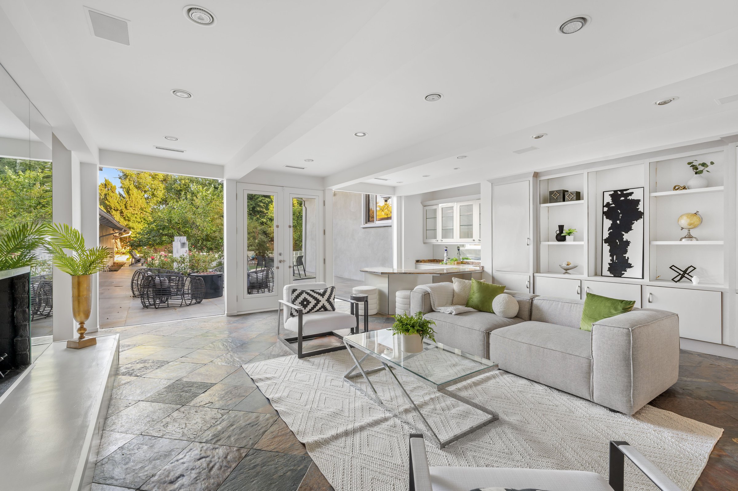 A modern living room with white furniture, fireplace, and open layout