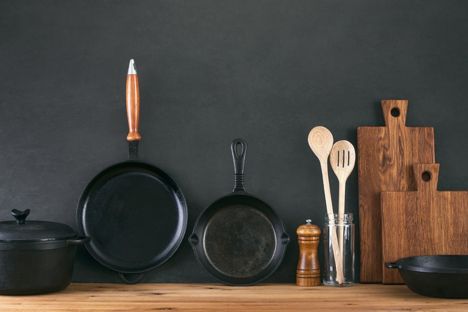 Kitchen utensils dark background with cast iron black kitchenware, front view of home kitchen table top
