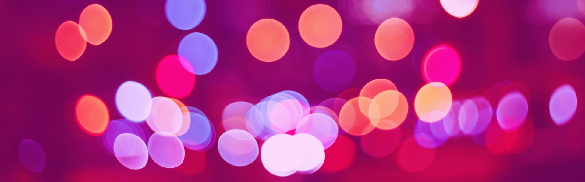 Abstract colorful blurry cinematic background bokeh. Defocused pink, violet, purple, yellow, red evening night street romantic lights. Web banner header for website.