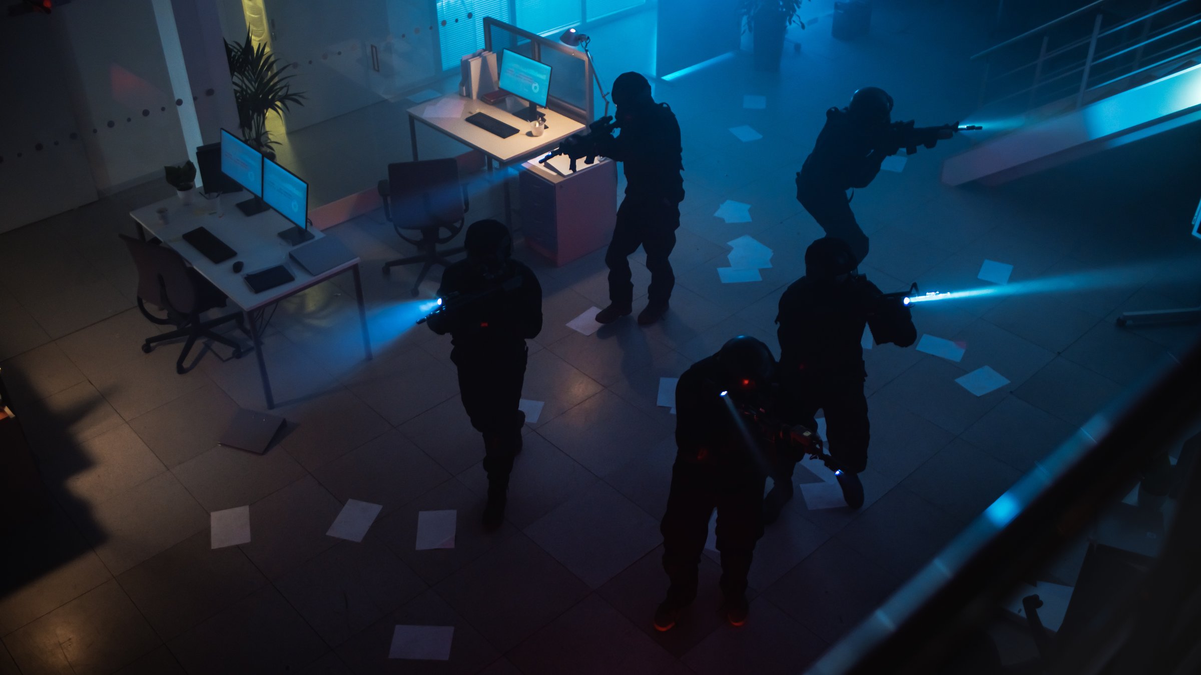 Masked Squad of Armed SWAT Police Officers Storm a Dark Seized Office Building with Desks and Computers. Soldiers with Rifles and Flashlights Move Forwards and Cover Surroundings. Above-view Camera.