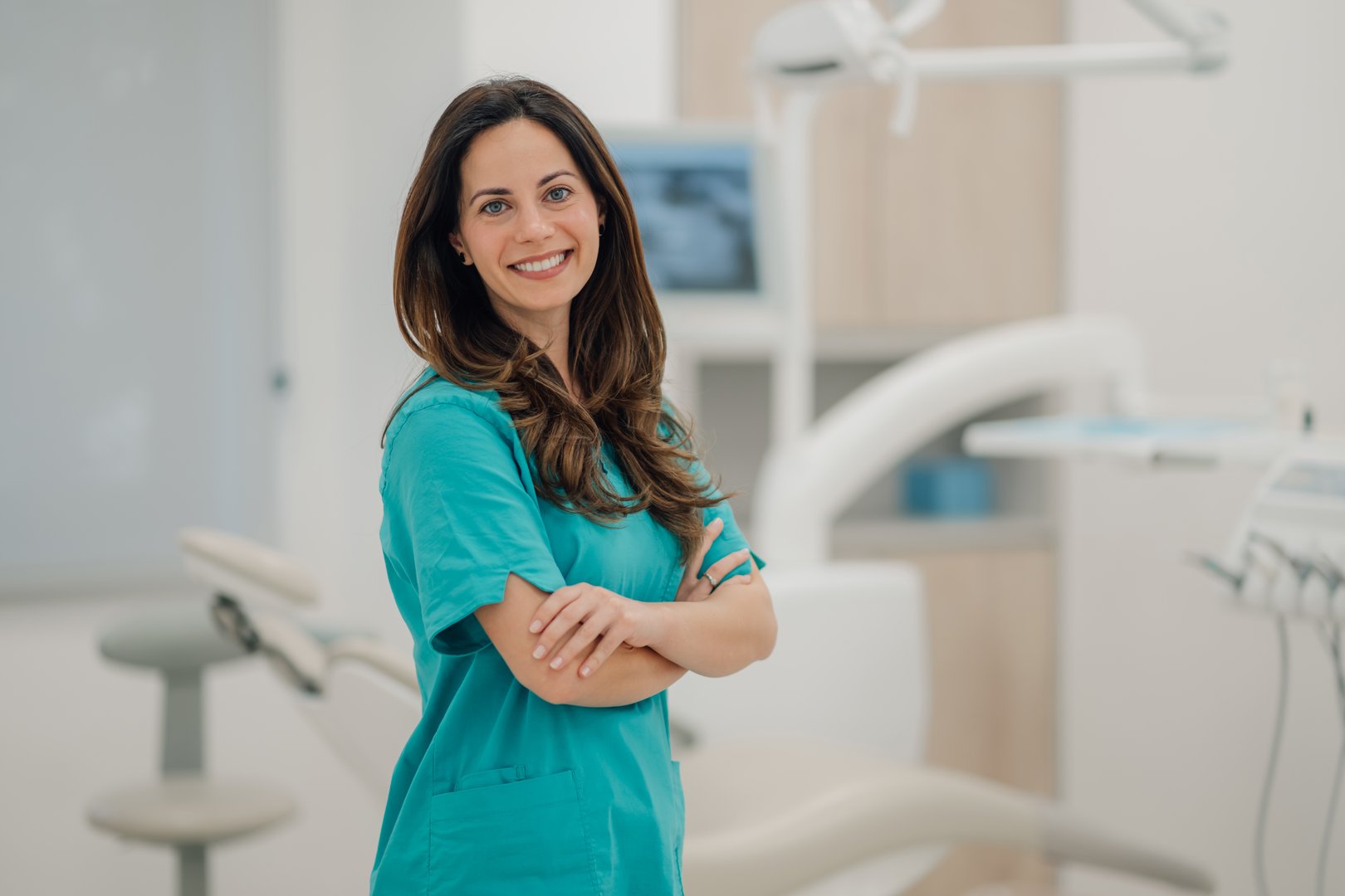 Confident dentist smiling with arms crossed in her modern dental clinic
