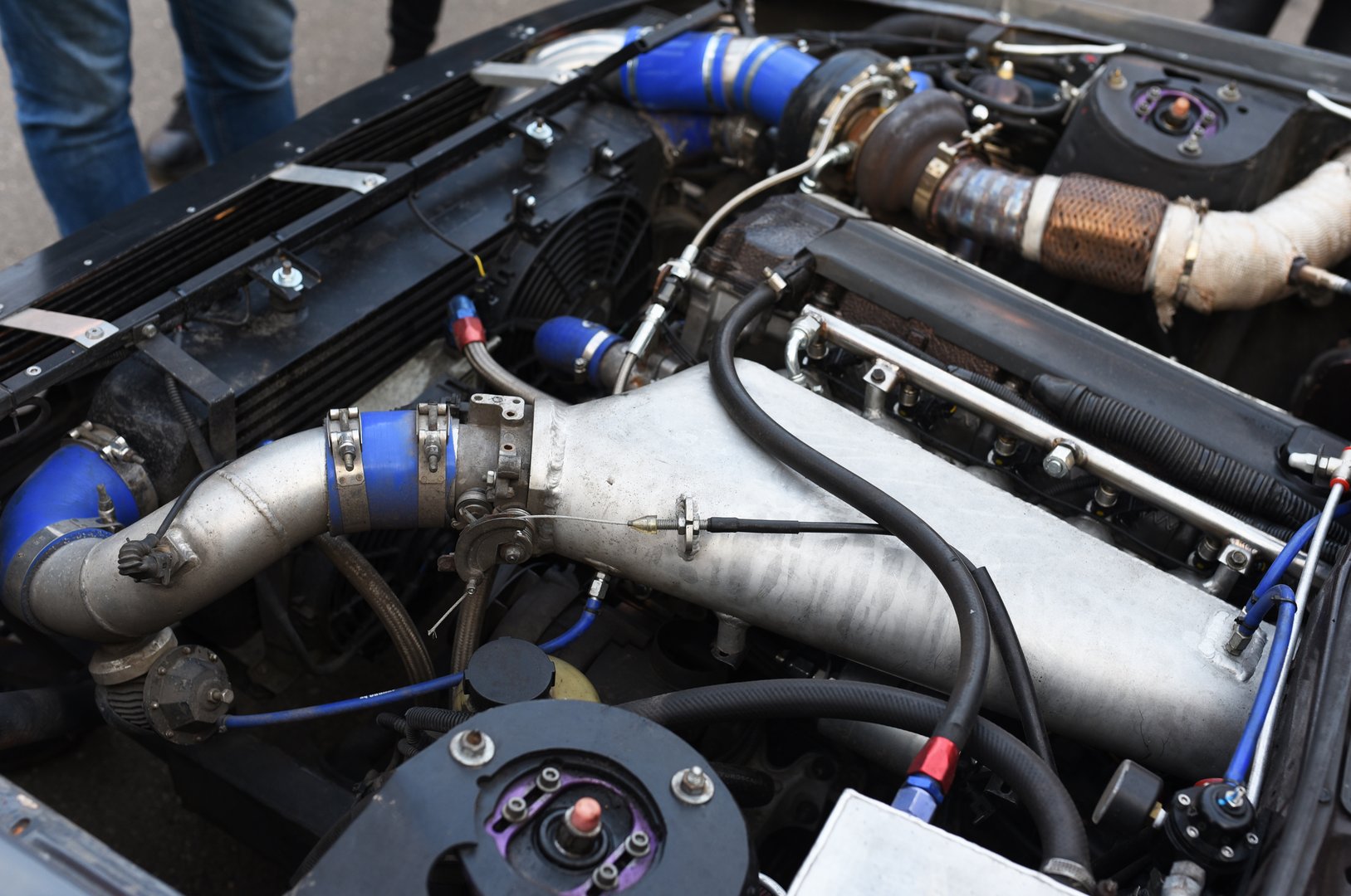 Sports car engine with turbine. An open race car hood on a pit stop while racing on a race track. Motor with turbocharger. Boos and tunning.