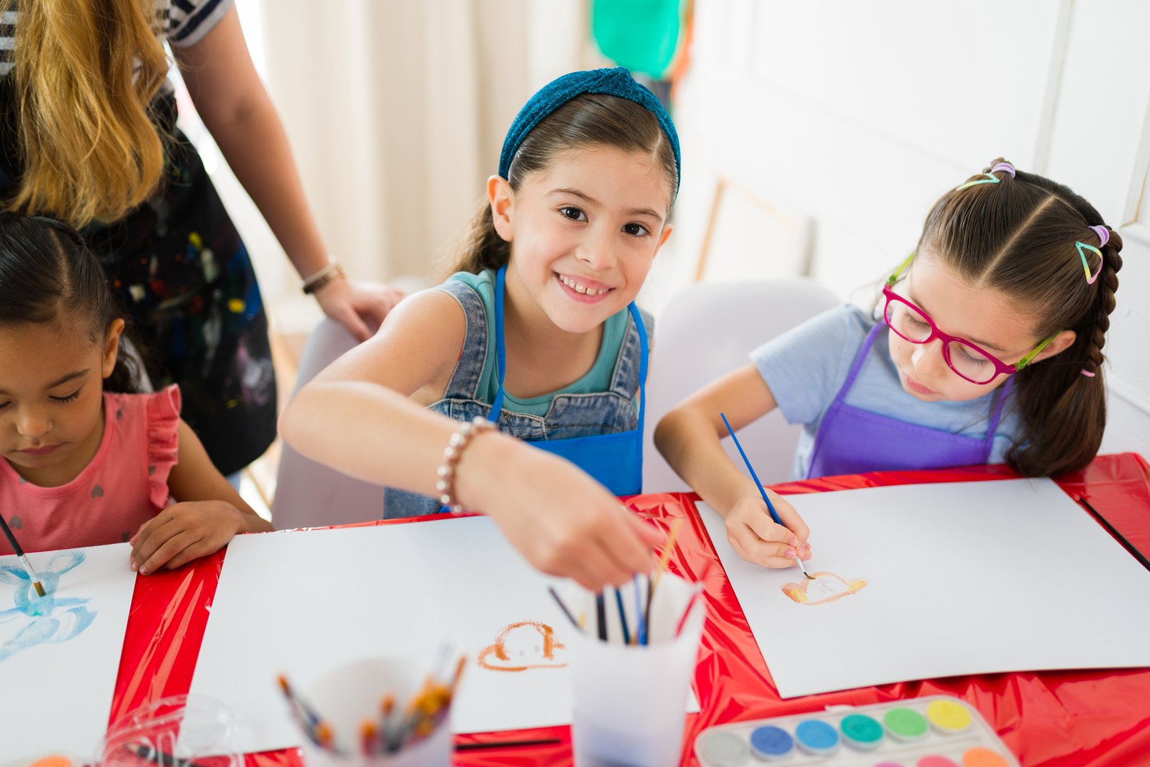 Hispanic elementary school students enjoying painting watercolors with their art teacher during a creative art class at school