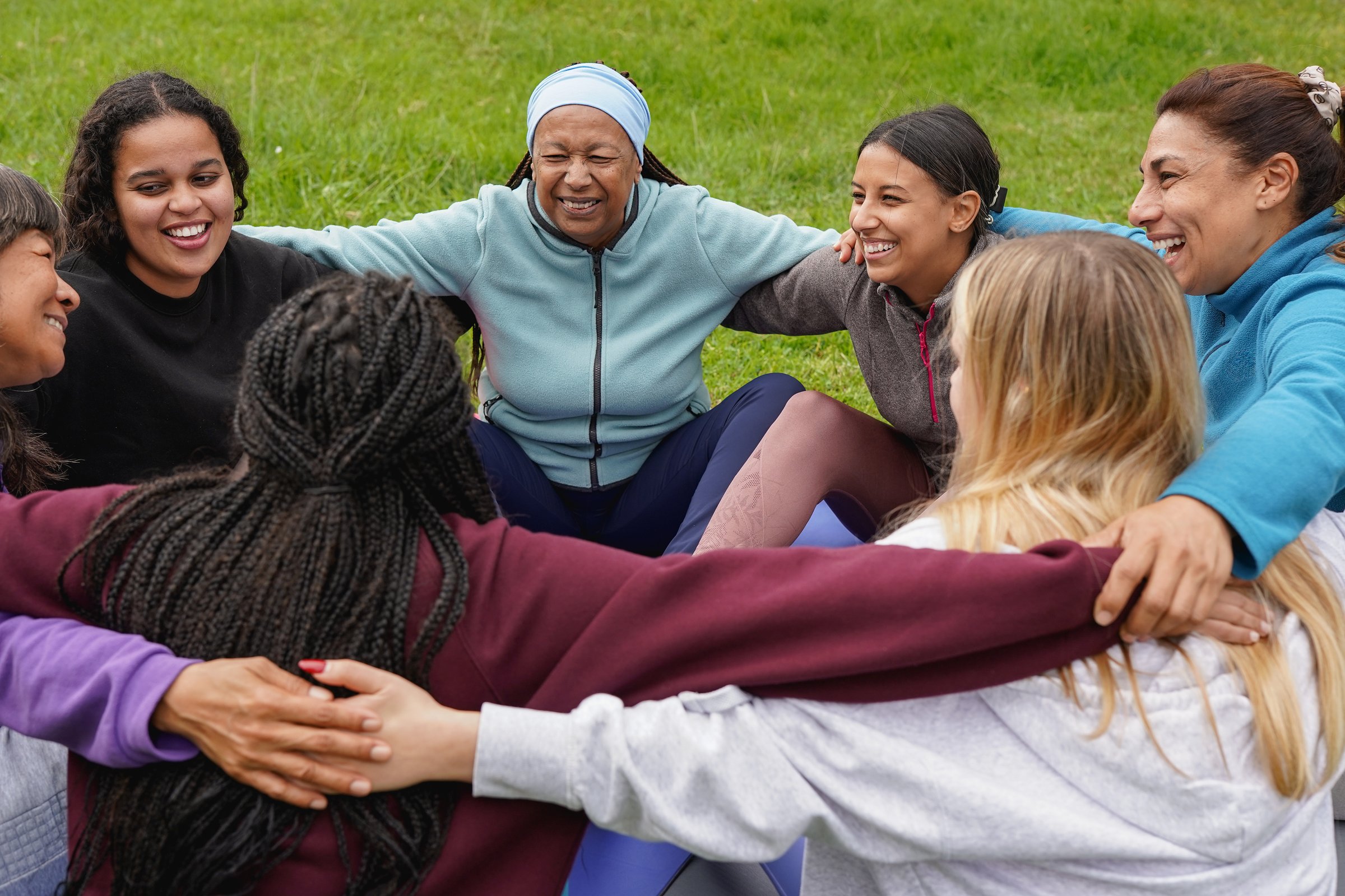 Women circle meeting each other and doing group meditation at city park