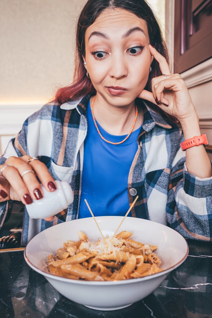 Woman hesitating to add salt to meal