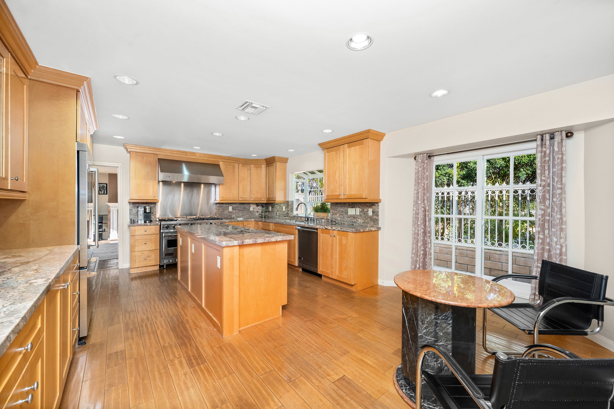 A kitchen with oak cabinets, oven, and breakfast table with chair in Encino, CA