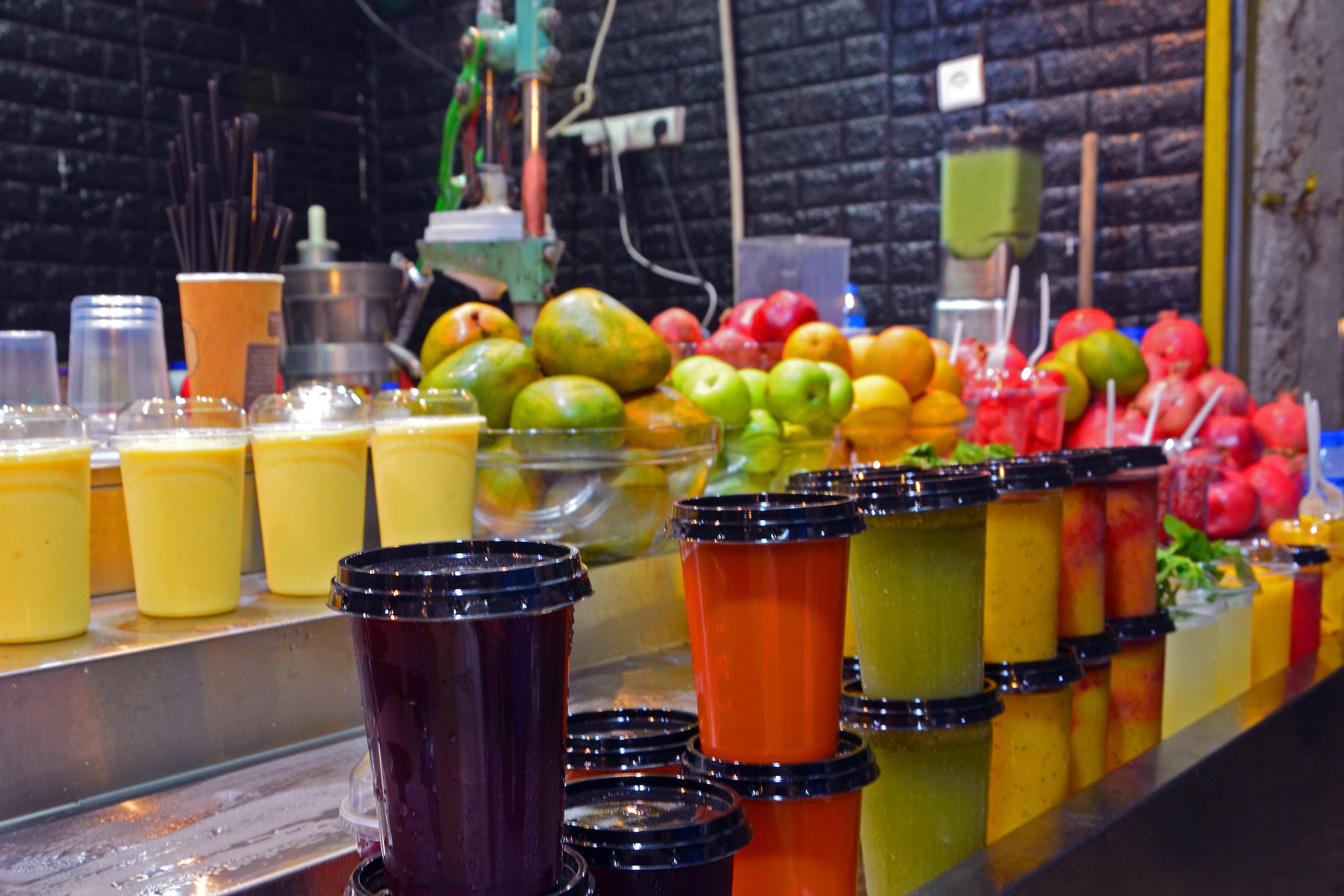 Multicolored fruit drinks and juice in plastic cups stand on the counter. market in jerusalem, israel.