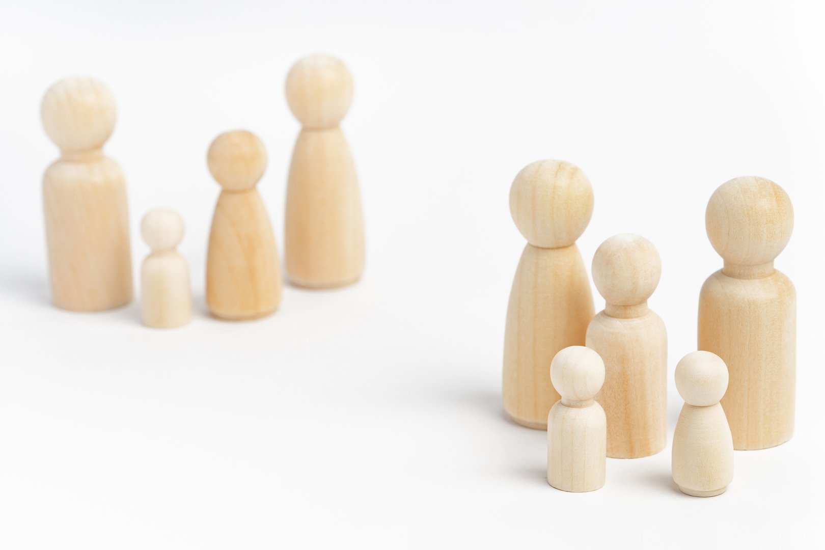 Family members made from wooden figurines on white background. Family with many children, multi-child or multi-member family. Isolation, social distancing between families