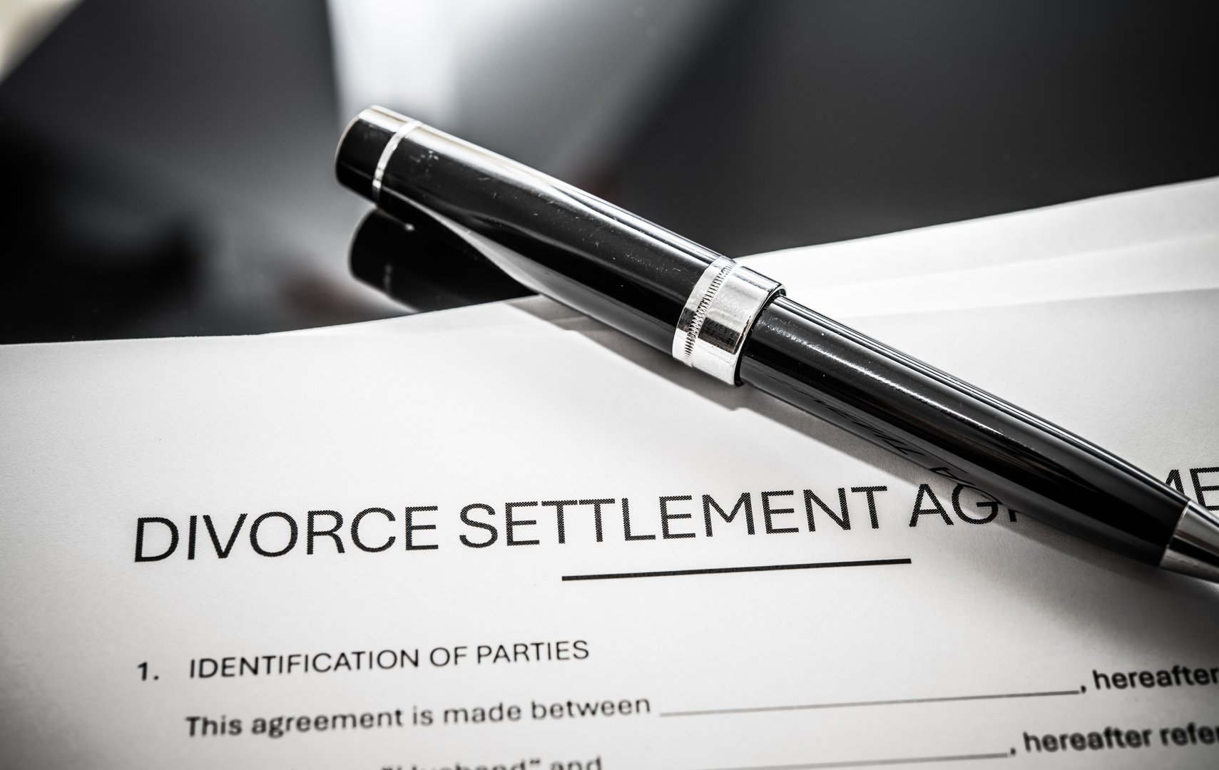 Divorce settlement agreement document on a table with a pen, representing legal separation and marital dissolution procedures for individuals seeking resolution after marriage.