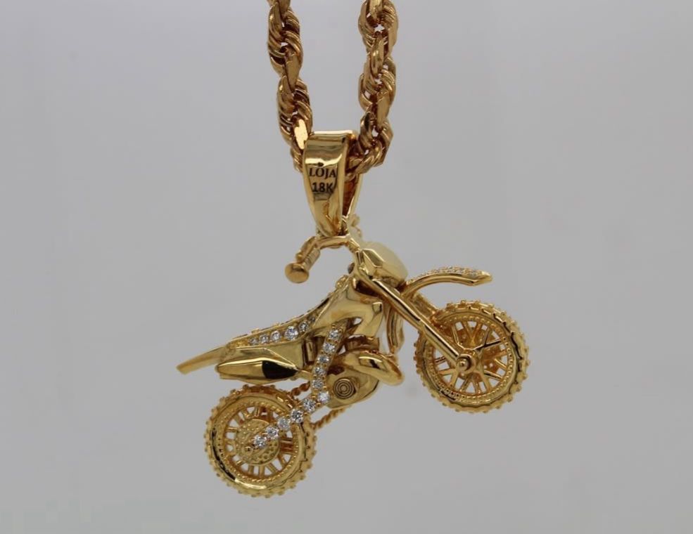Gold motorcycle pendant with diamond accents on a twisted gold chain, intricately detailed and shiny.
