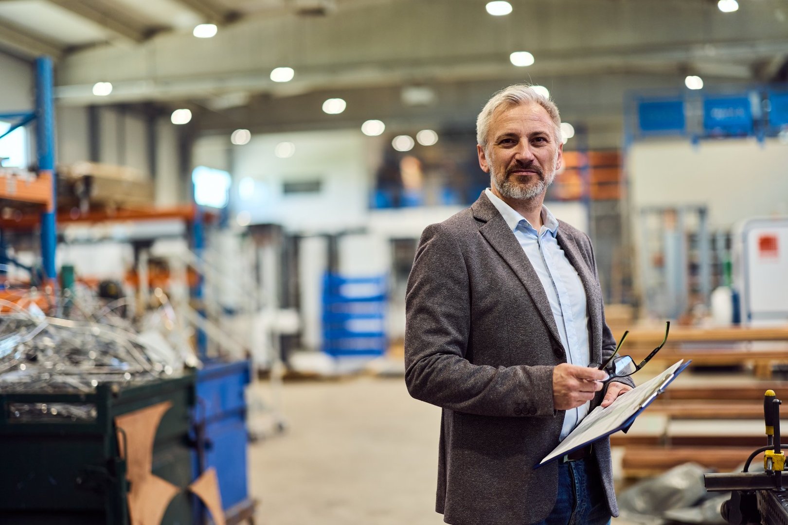Mature professional manager standing confidently in a large industrial warehouse