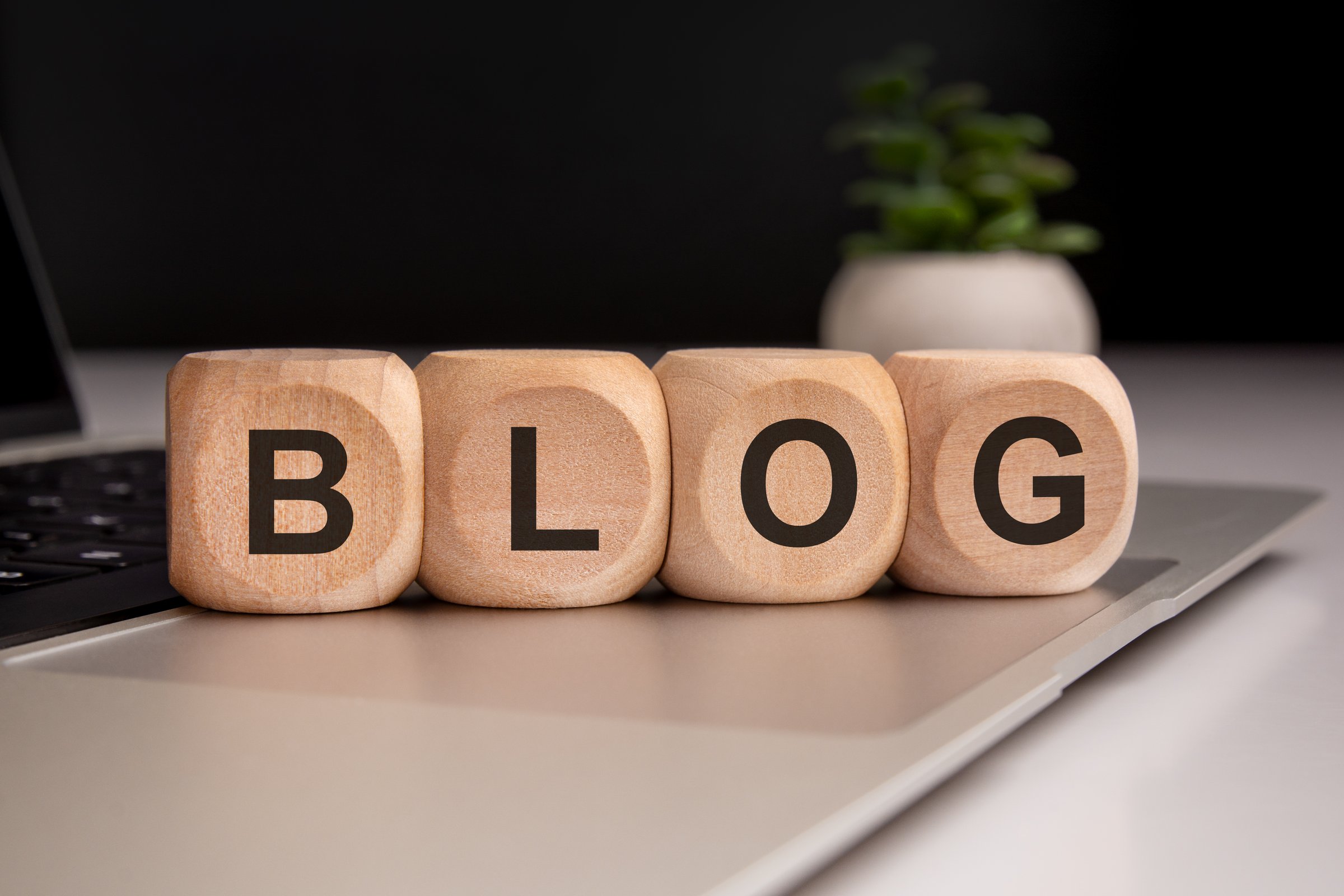 Wooden cubes spelling 'BLOG' rest on a laptop s surface, symbolizing digital content creation, online writing, and modern communication. Ideal for illustrating blogging and social media themes